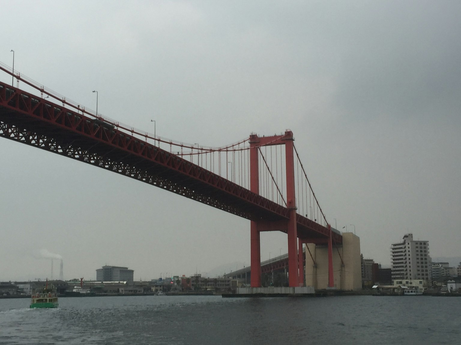 Jembatan merah membentang di atas air dengan langit mendung