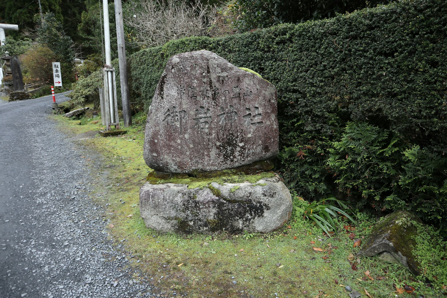 一块石碑在碎石路旁边，周围是绿色植物和苔藓