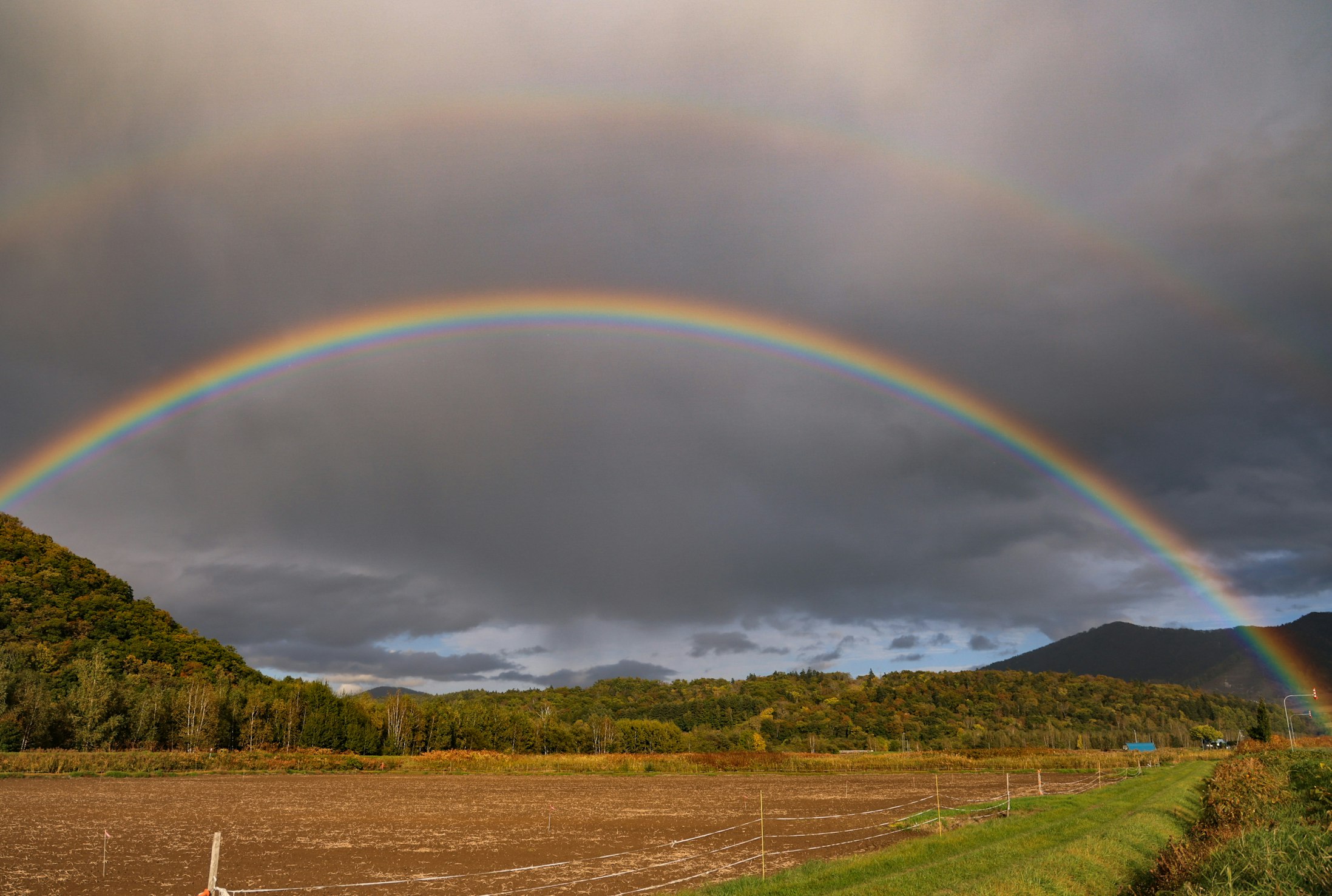 rainbow over hills and pasture landscape