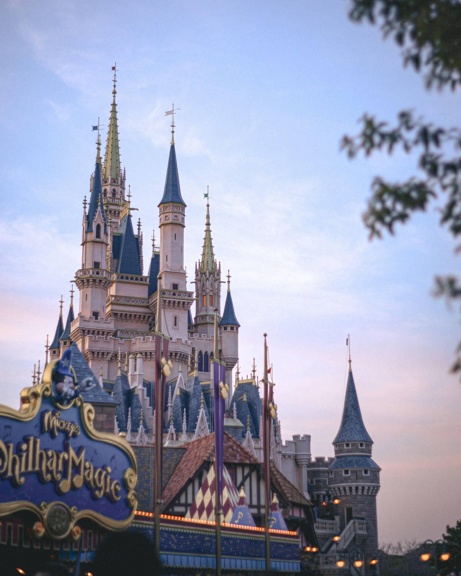 Disney castle with spires under a beautiful sky and amusement park sign