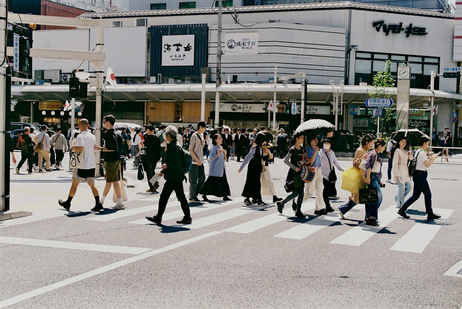 People crossing a street with umbrellas in a busy urban area