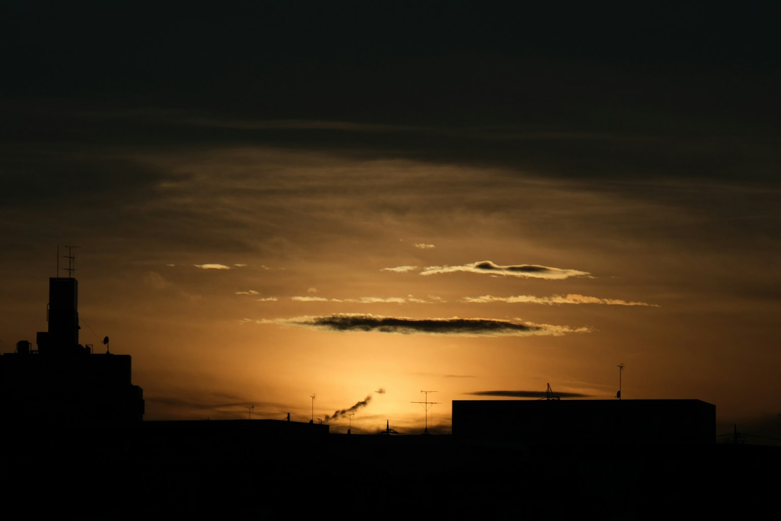 Silhouette d'une ville au coucher du soleil avec des nuages dans un ciel sombre