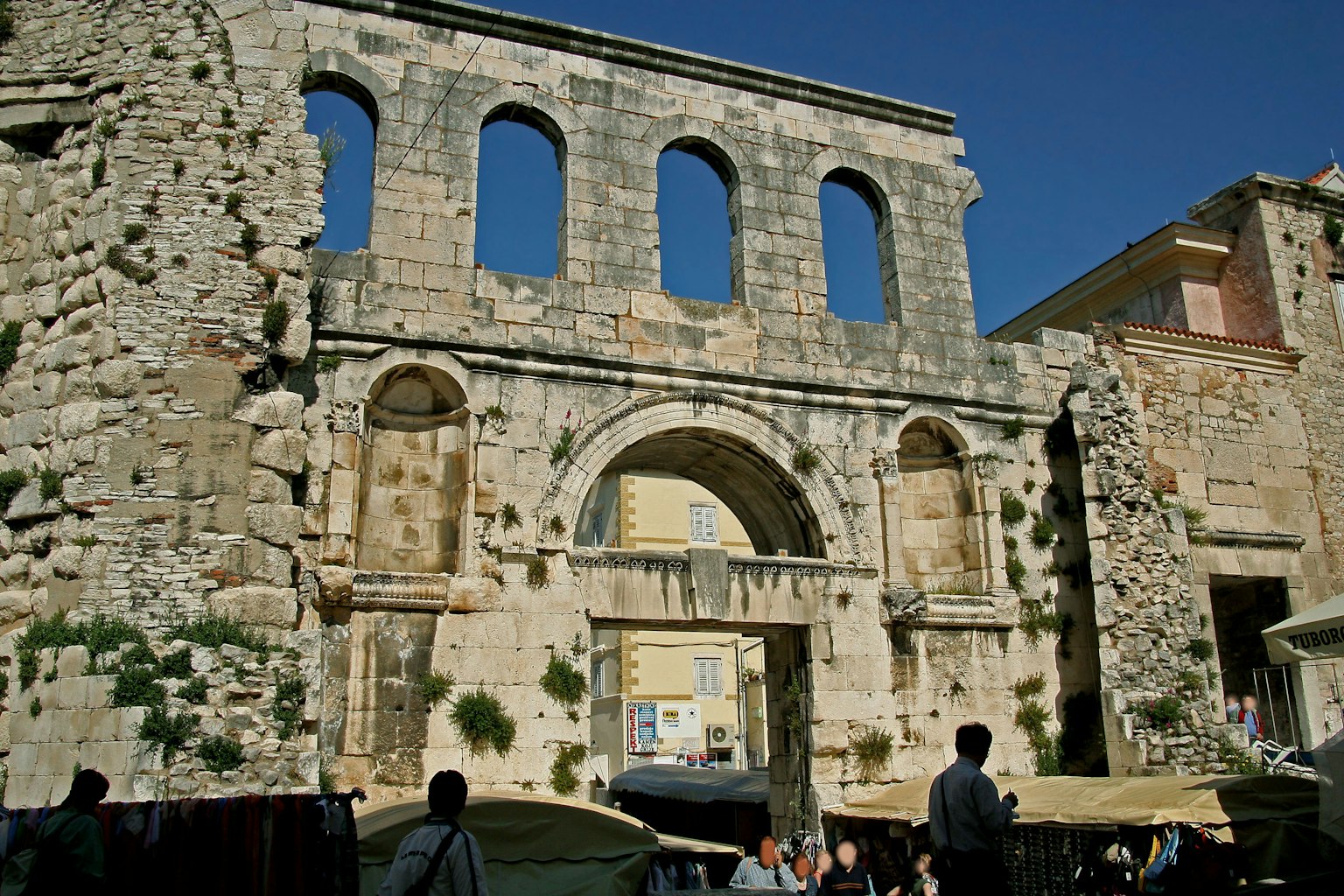 Ancient stone architectural ruins with market under blue sky