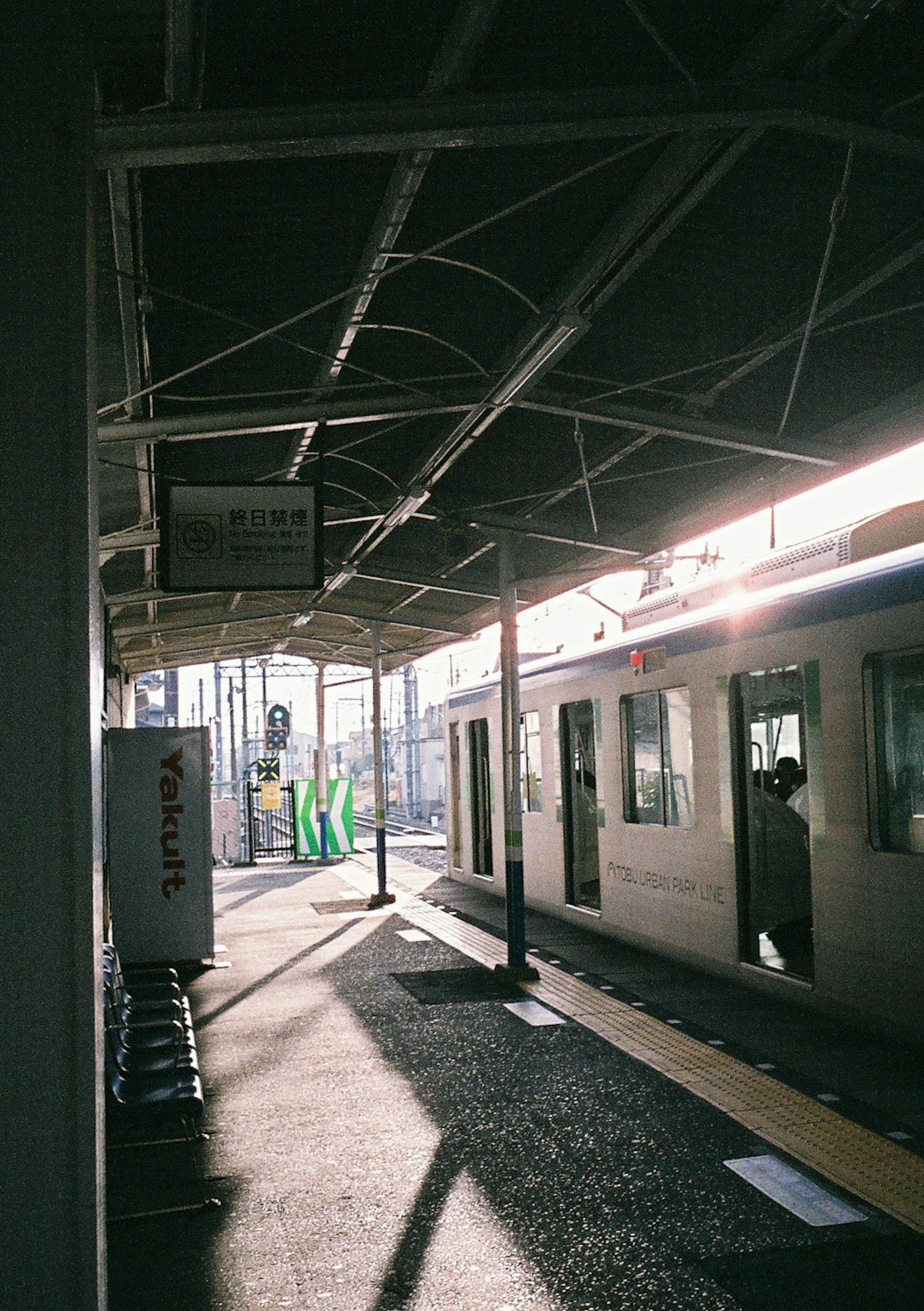 Treno in una stazione con un passeggero e luce solare