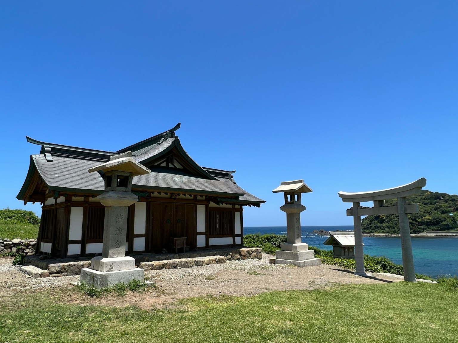 Traditional Japanese shrine with lanterns under a clear blue sky