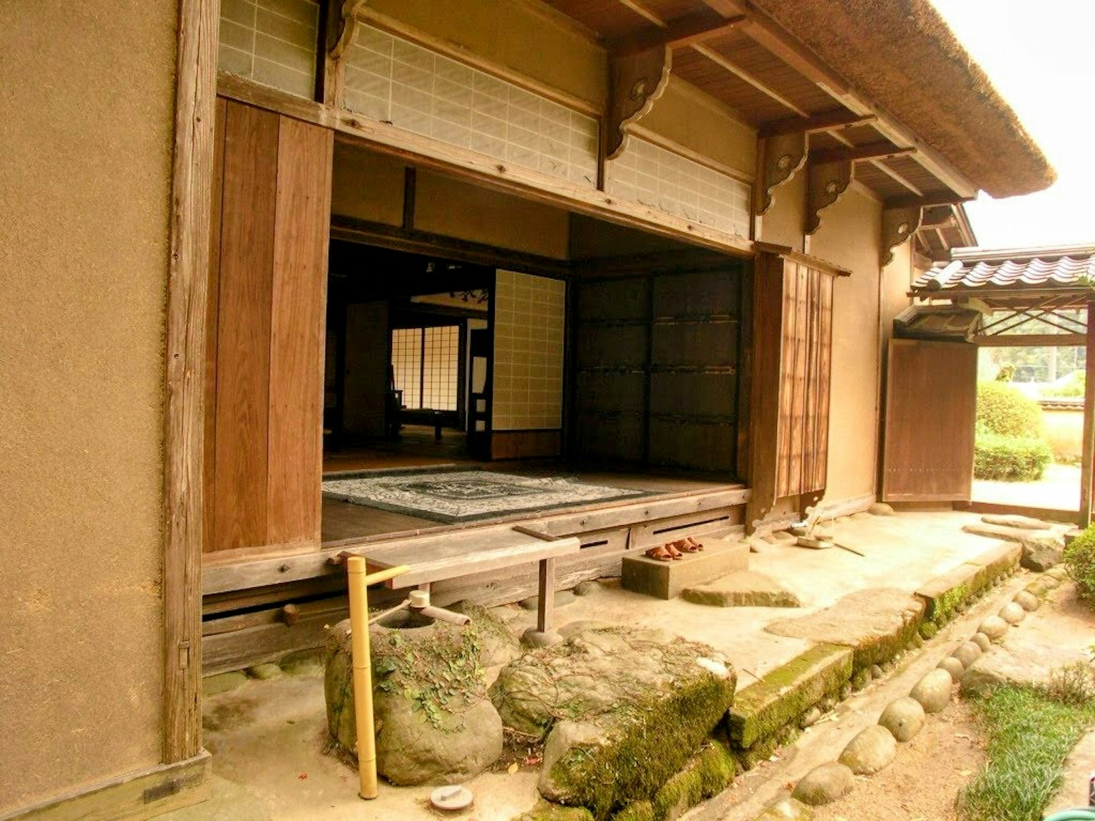 Vue extérieure d'une maison japonaise traditionnelle avec des portes en bois et des murs en terre ouverts sur le jardin