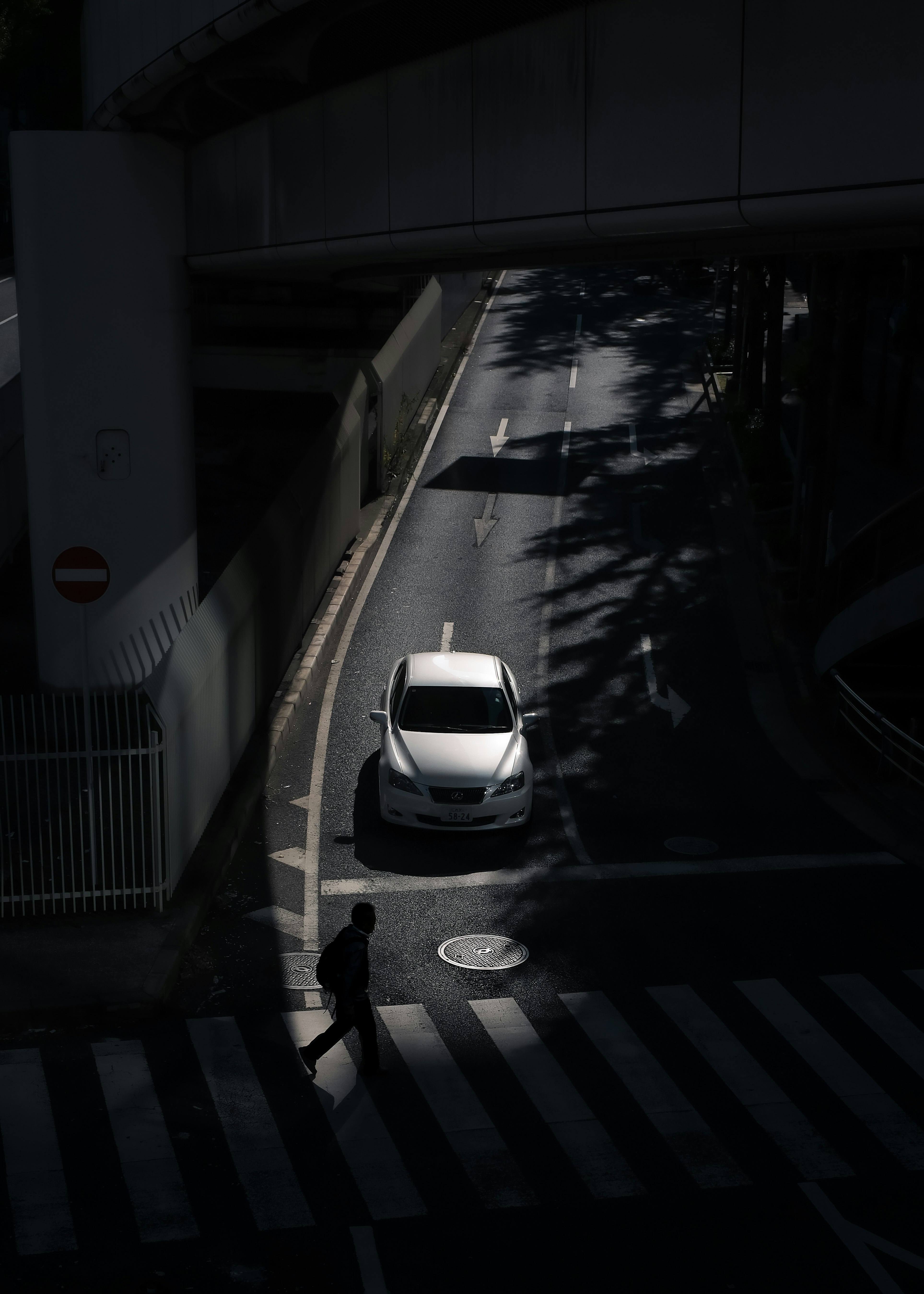 Une voiture et une personne encadrées par des ombres à un carrefour
