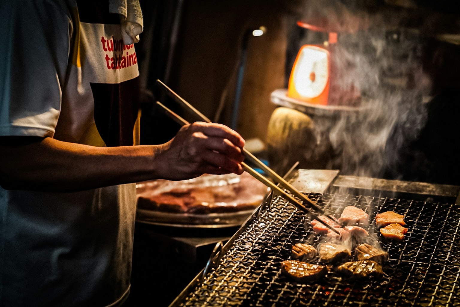 Koch grillt Fleisch mit Stäbchen und Rauch
