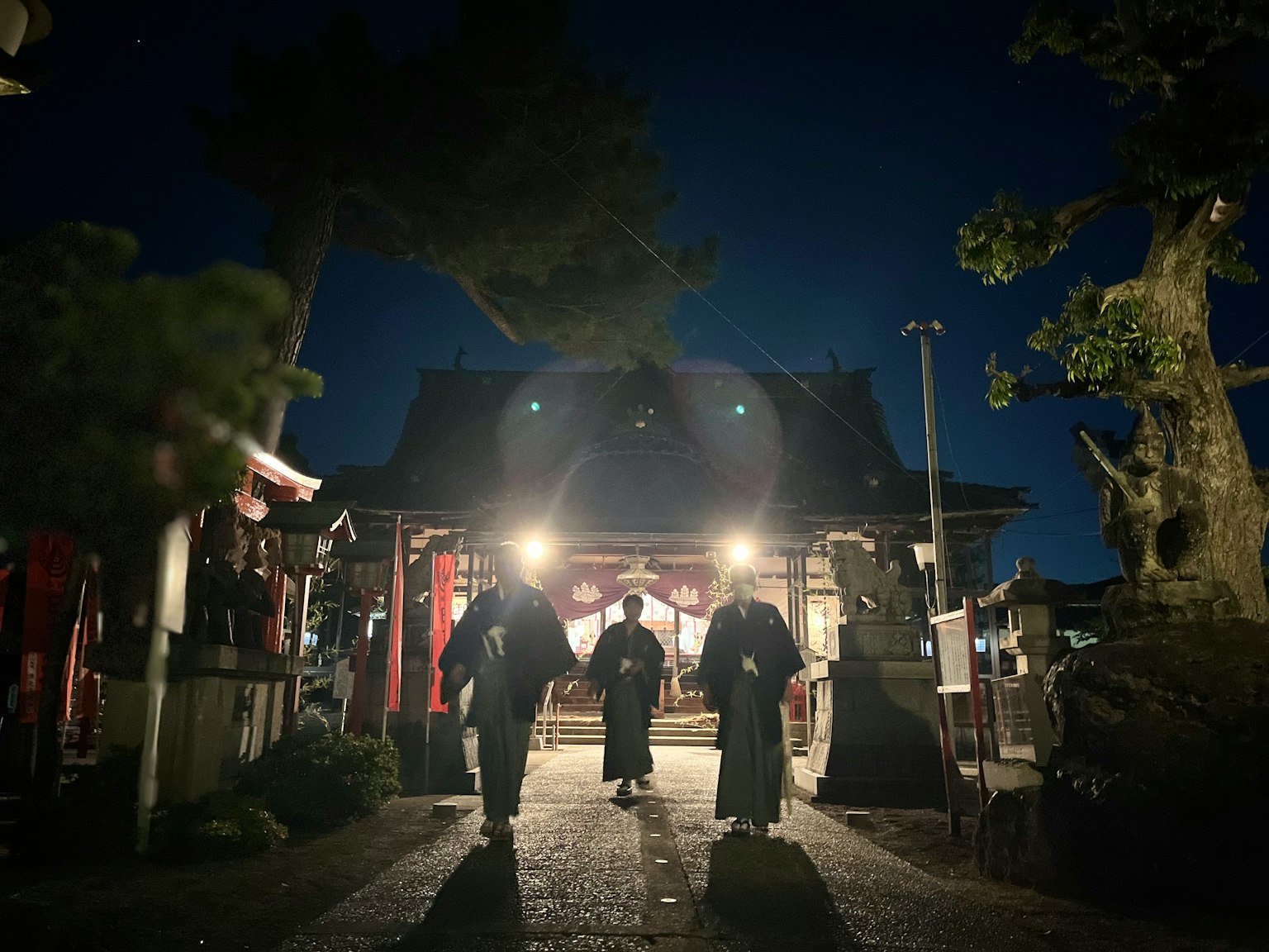 夜间在灯光照耀下的神社走动的人们的轮廓