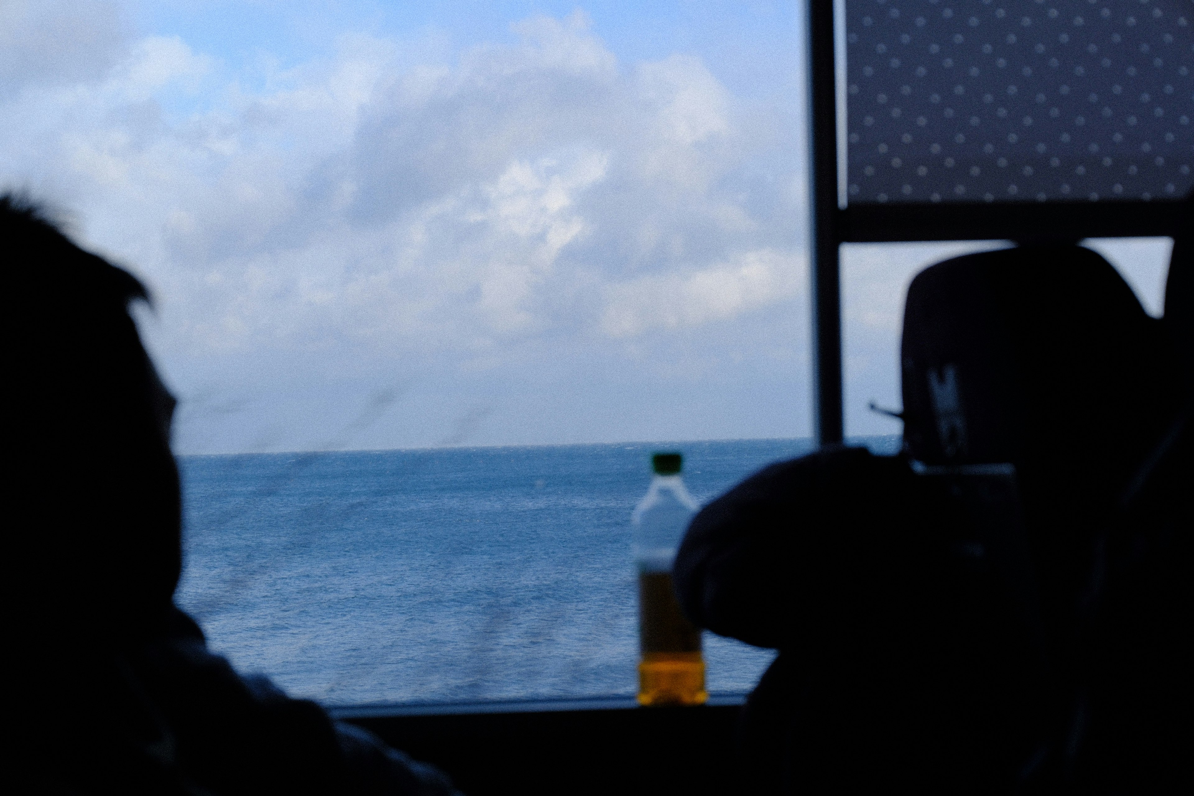 Silhouette di persone su una barca che guardano mare e cielo