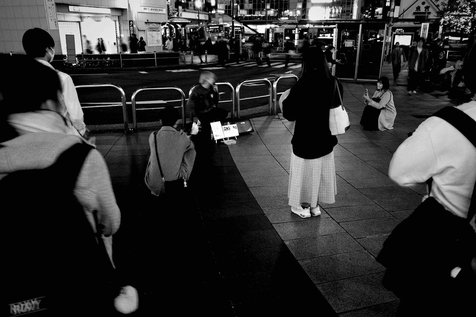 Black and white photo of a bustling urban scene at night with people gathered