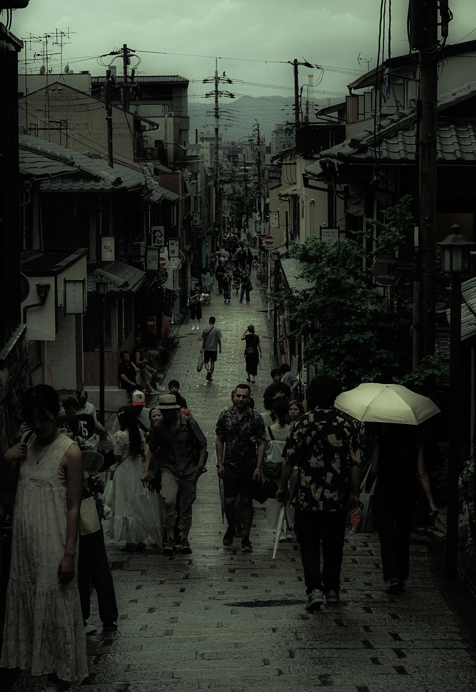 雨の中を歩く人々がいる古い街並みの風景