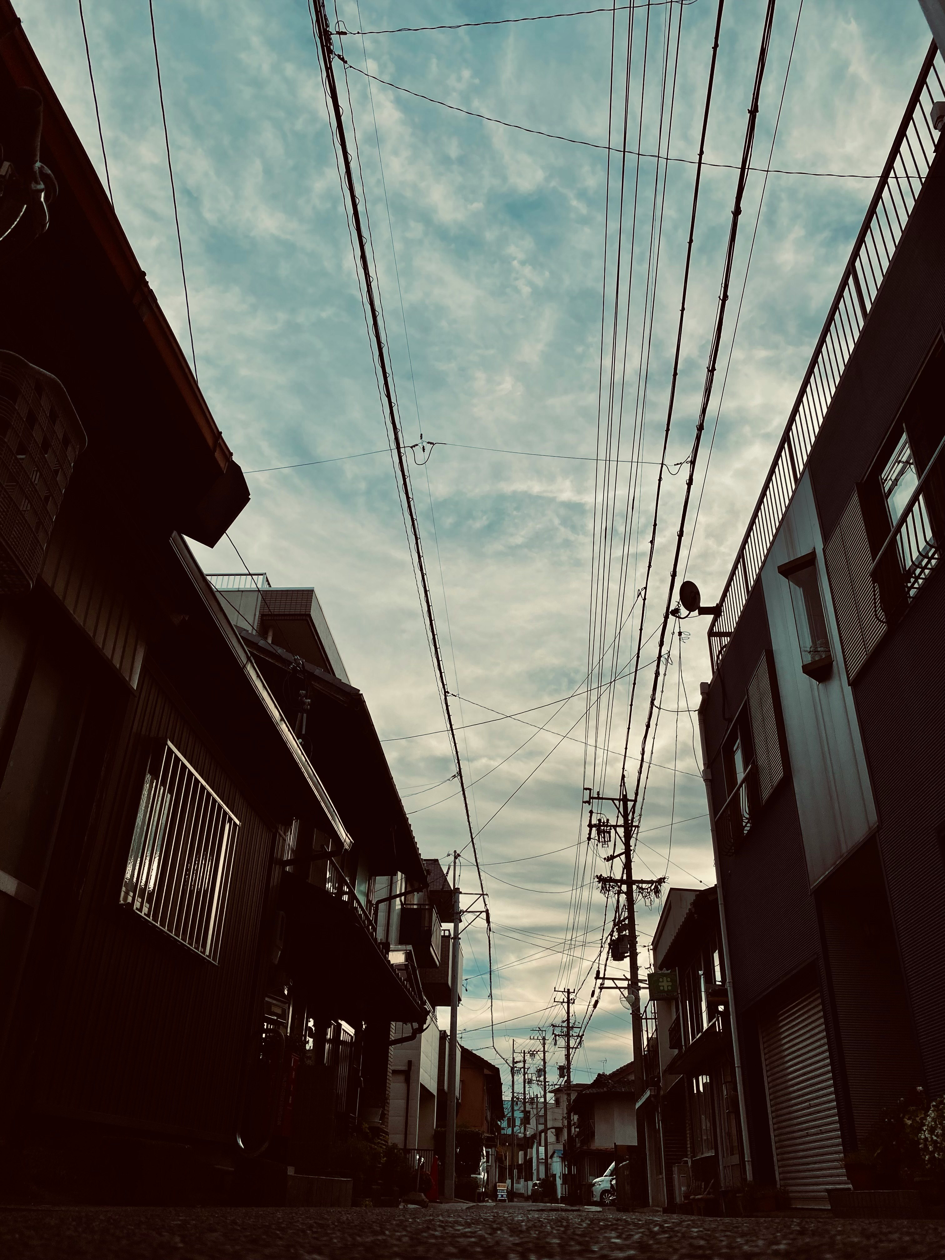 空に広がる雲の下の路地に並ぶ建物