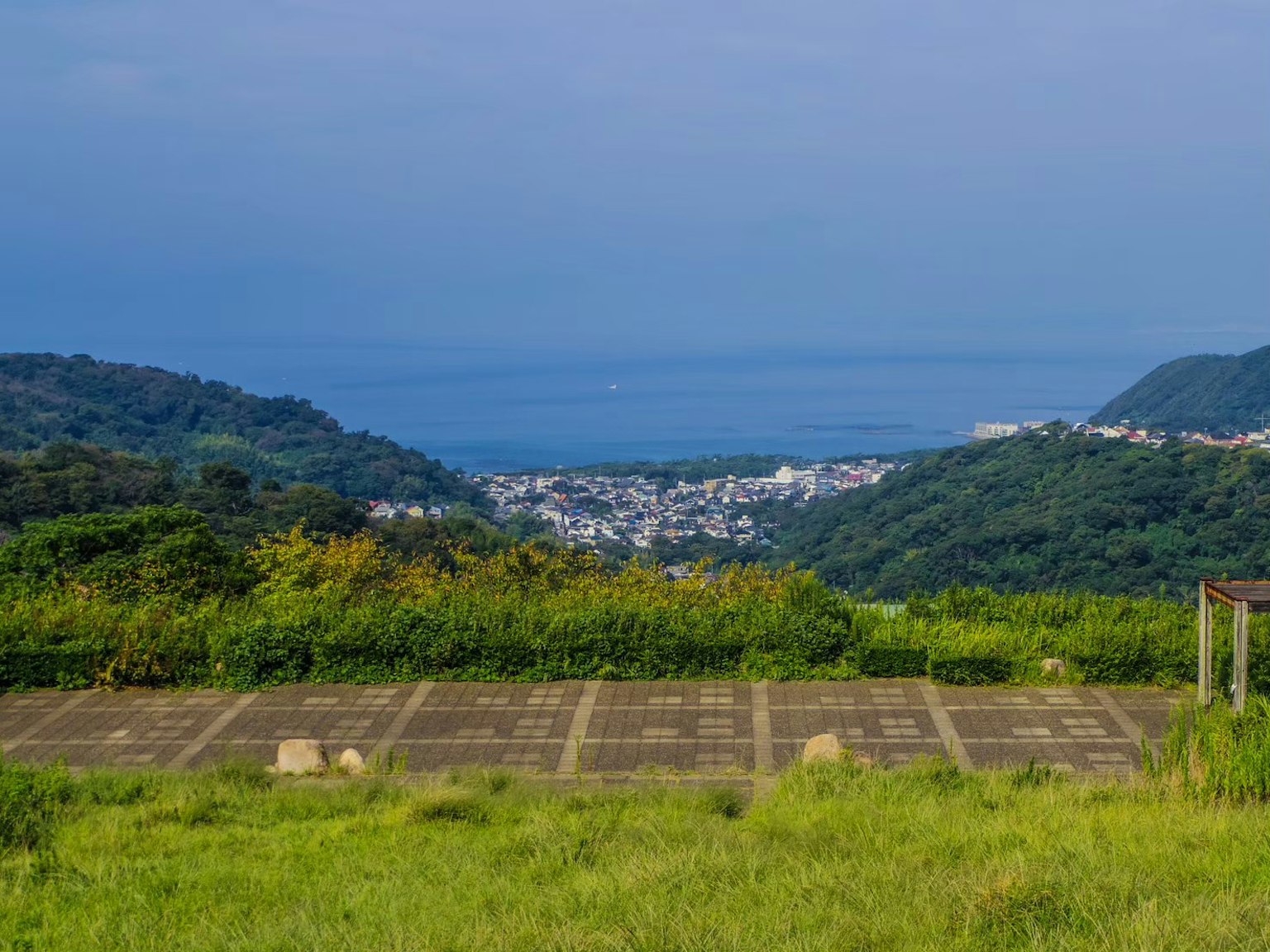 Vista escénica desde una colina verde que mira al mar y a un pueblo