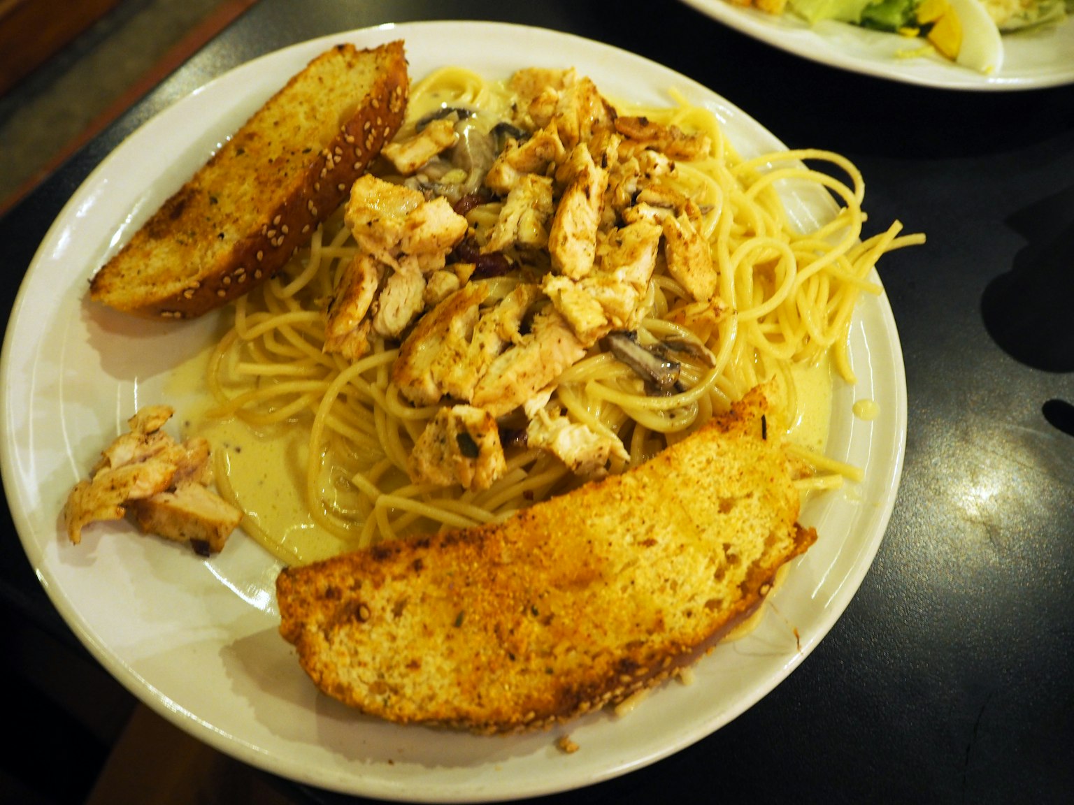 Pasta cremosa de pollo con pan de ajo en un plato