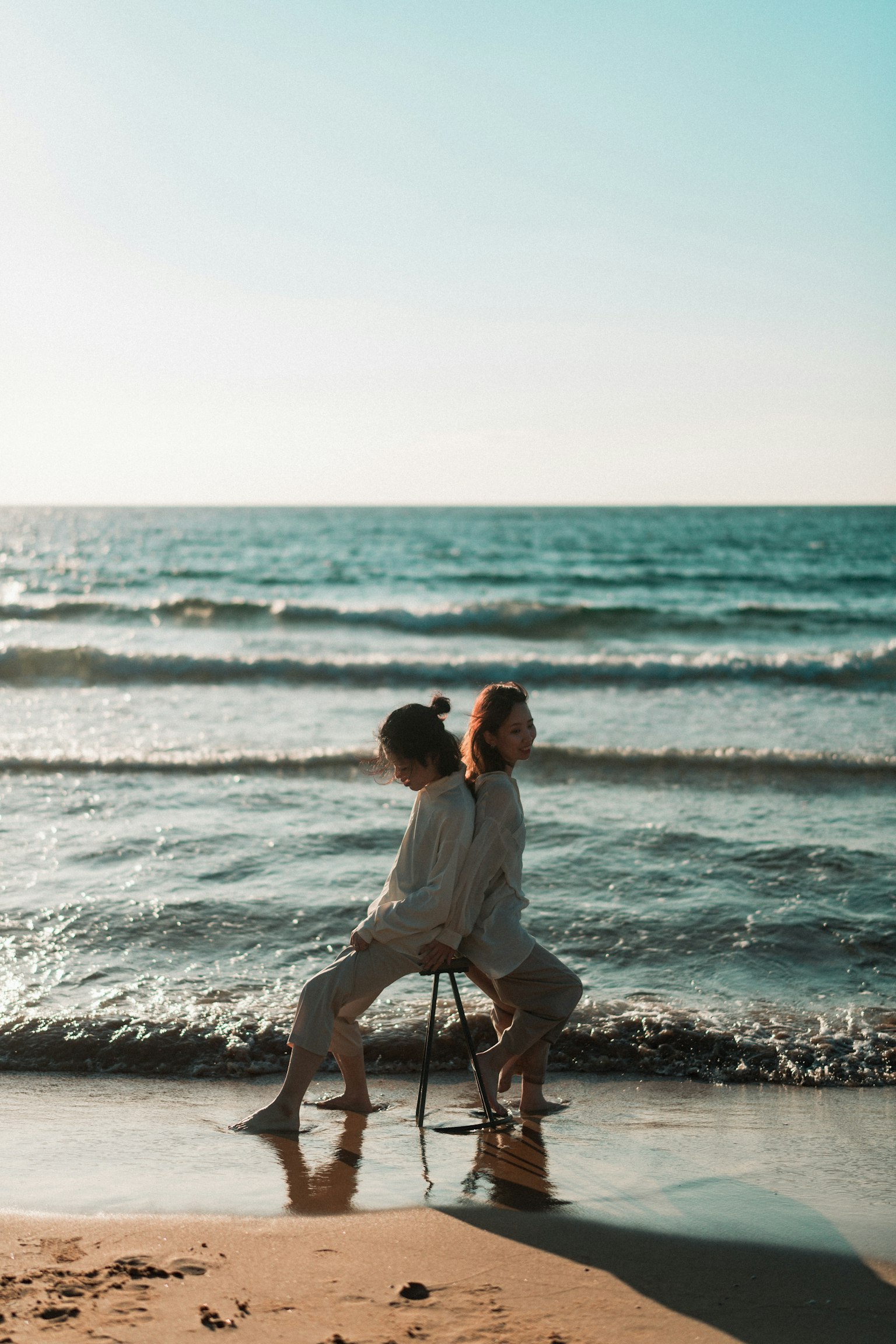 คนสองคนที่นั่งหลังชนกันบนเก้าอี้ที่ชายหาด