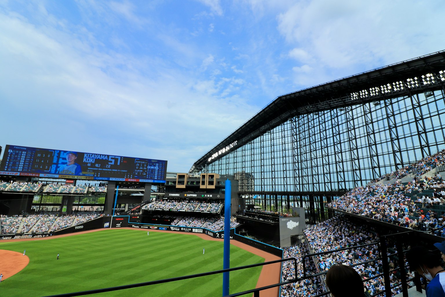 View of a baseball stadium with a glass facade and crowd in the stands