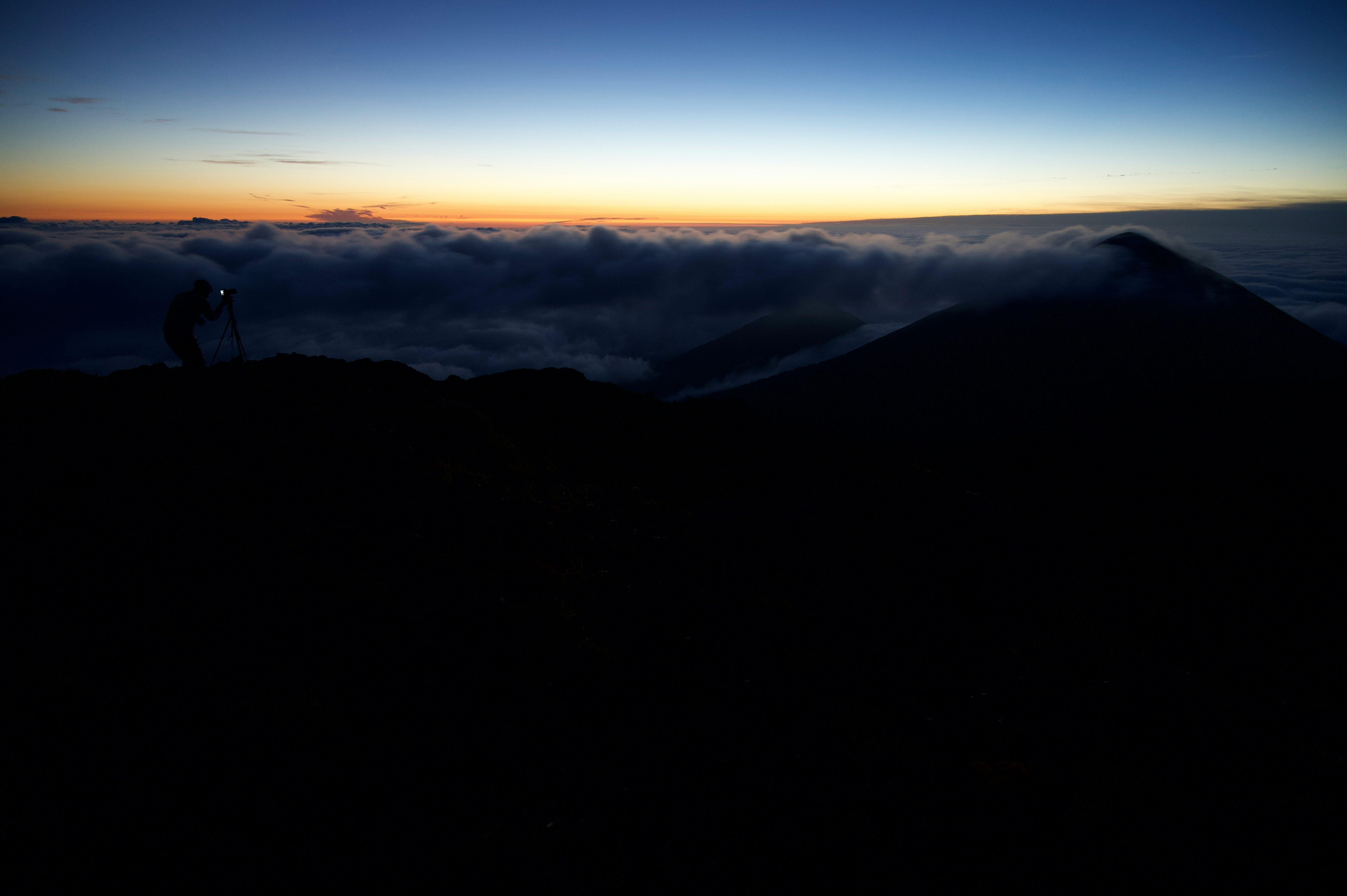crêtes de montagnes au-dessus d’une mer de nuages au coucher du soleil