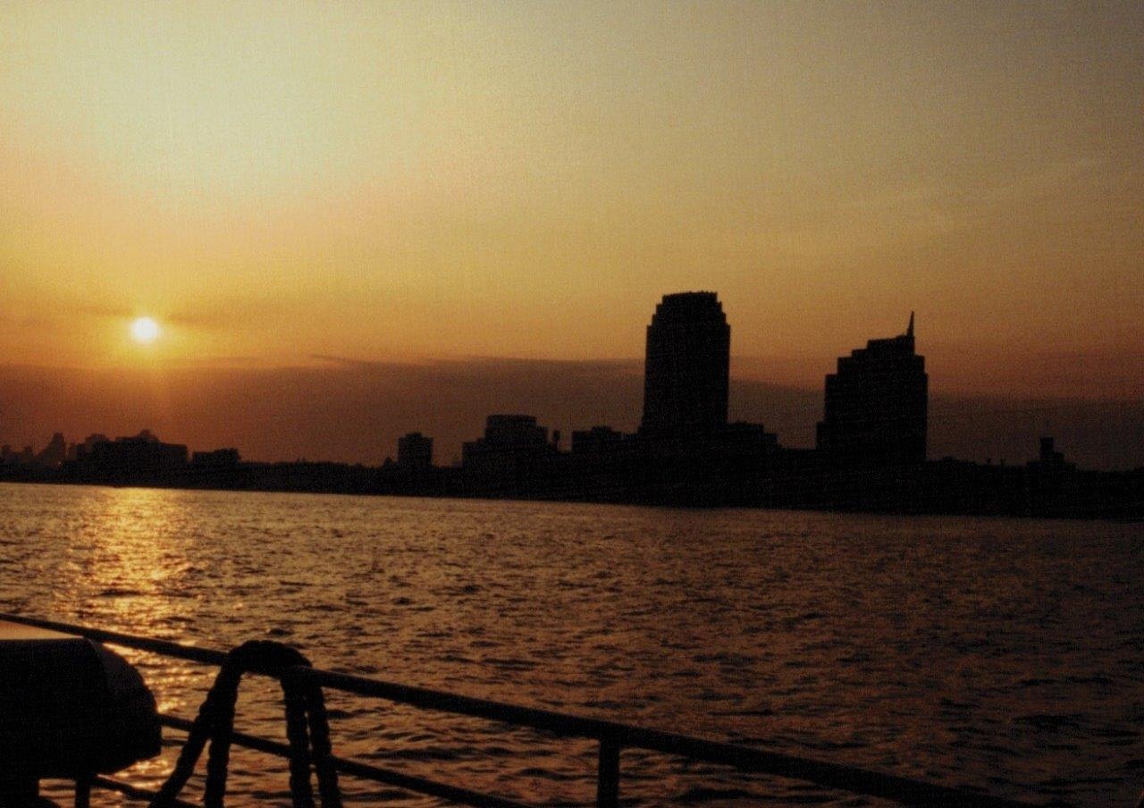 夕暮れの川沿いに並ぶシルエットの高層ビル群
