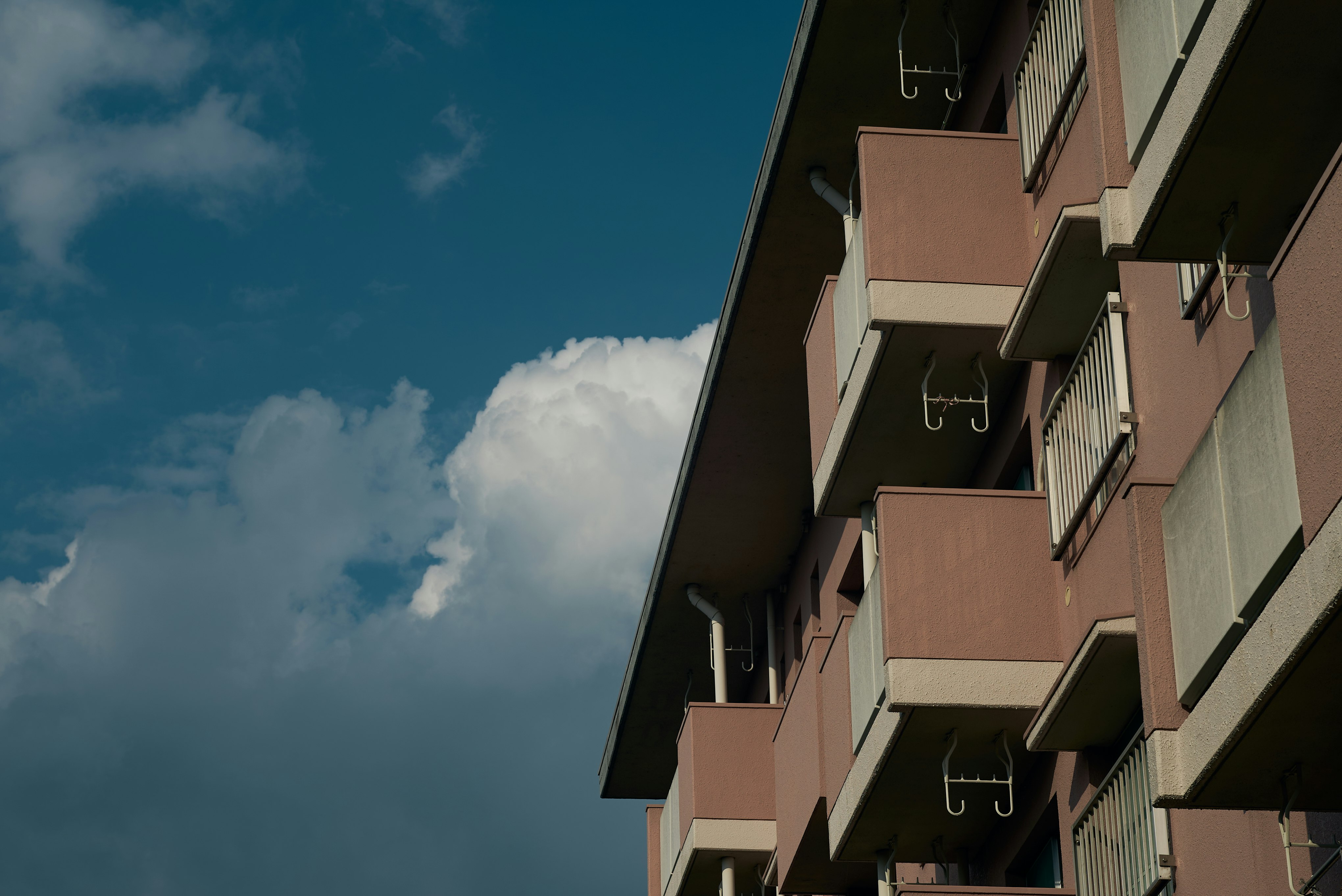 青空の下に並ぶ集合住宅の外壁とバルコニー