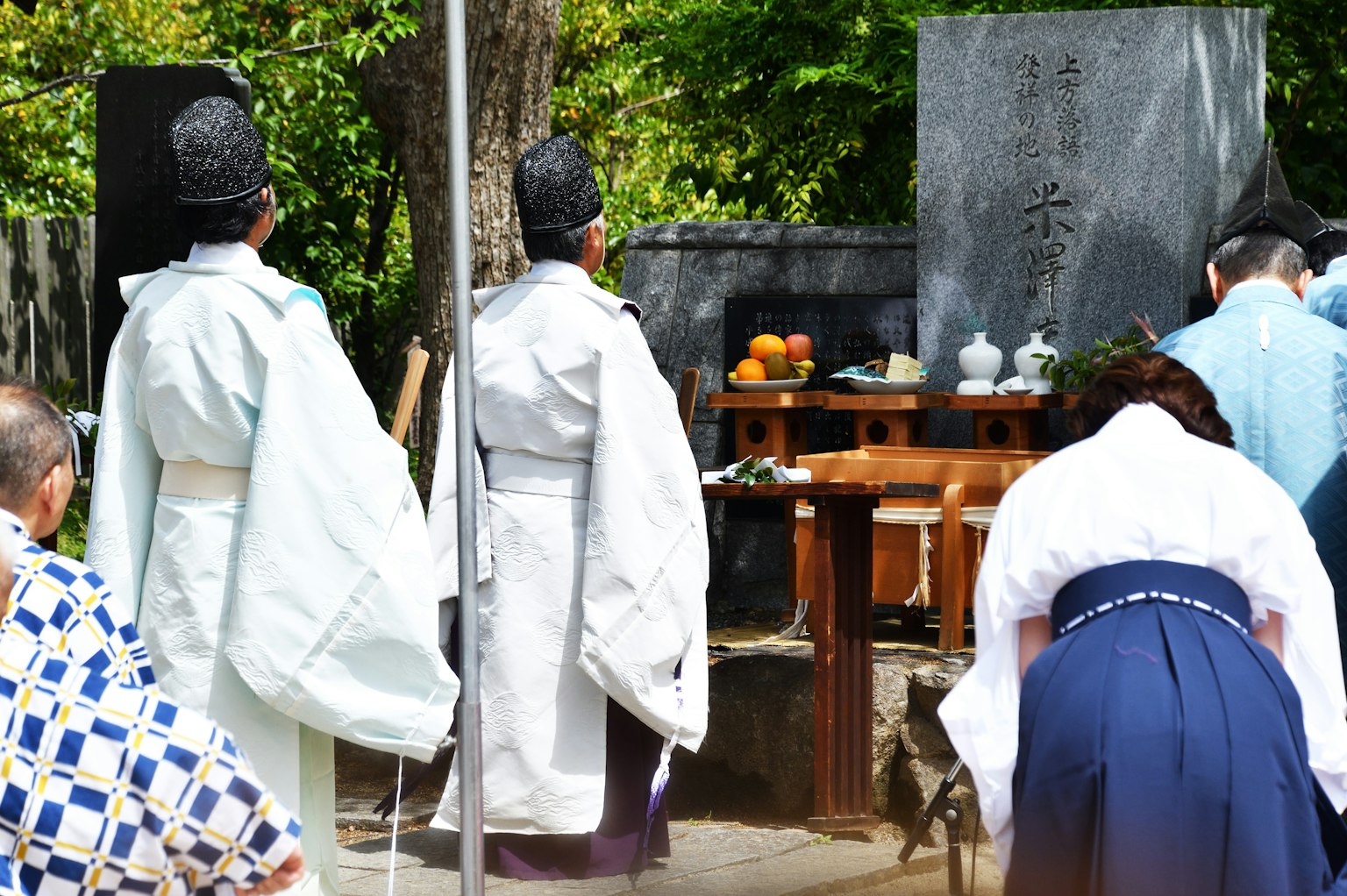 Due sacerdoti shintoisti in abiti bianchi in piedi davanti a un altare durante una cerimonia del santuario