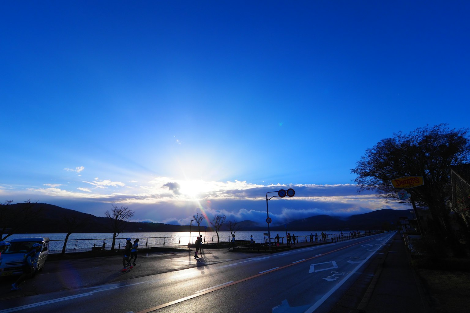 Scenic view of a lake under a blue sky with clouds and a road