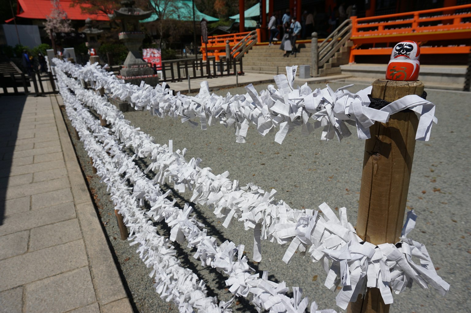 Una escena en un santuario con omikuji blancos colgados en una valla de madera