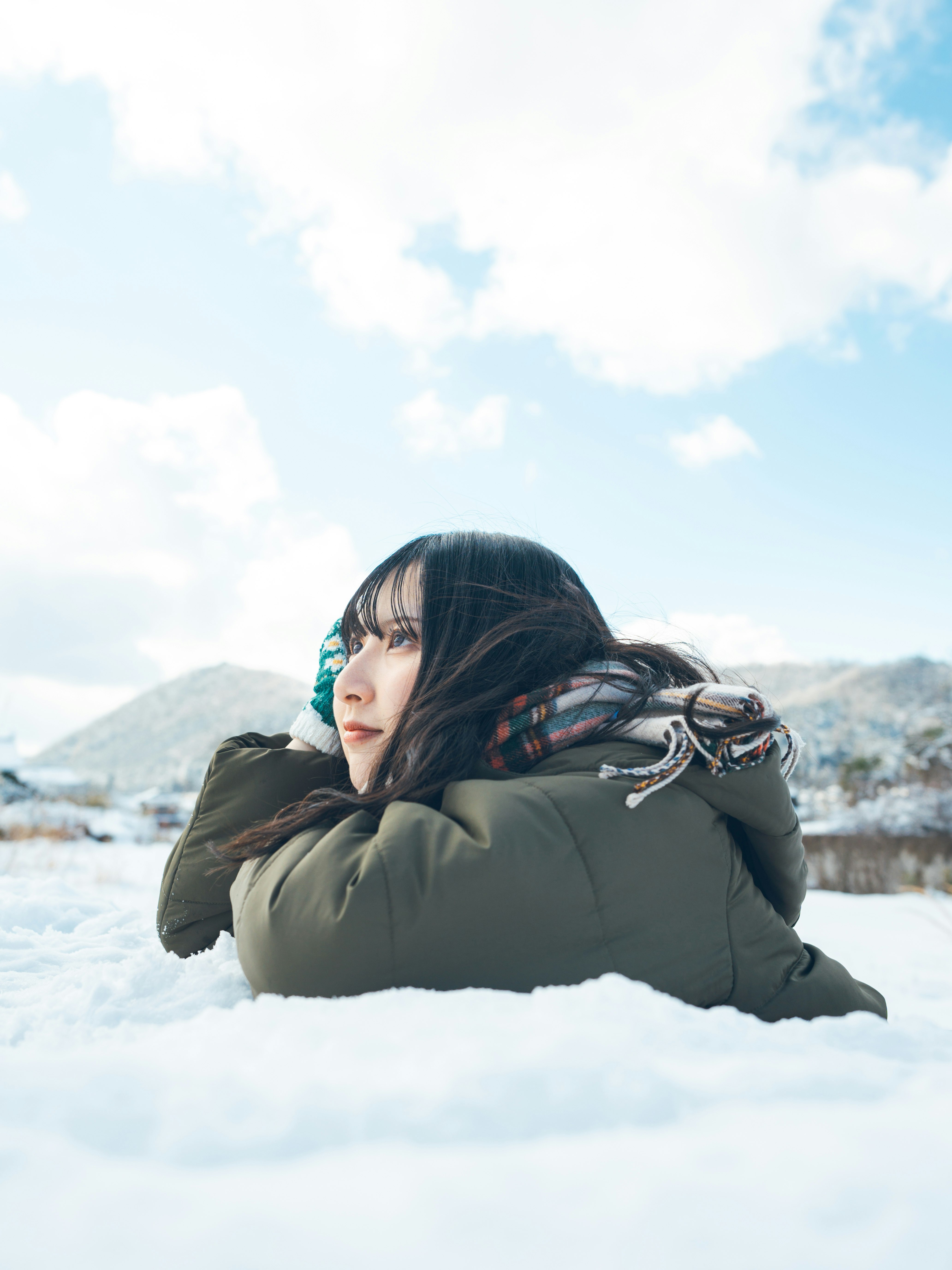 Seitenprofil einer Frau im Wintermantel auf verschneitem Feld