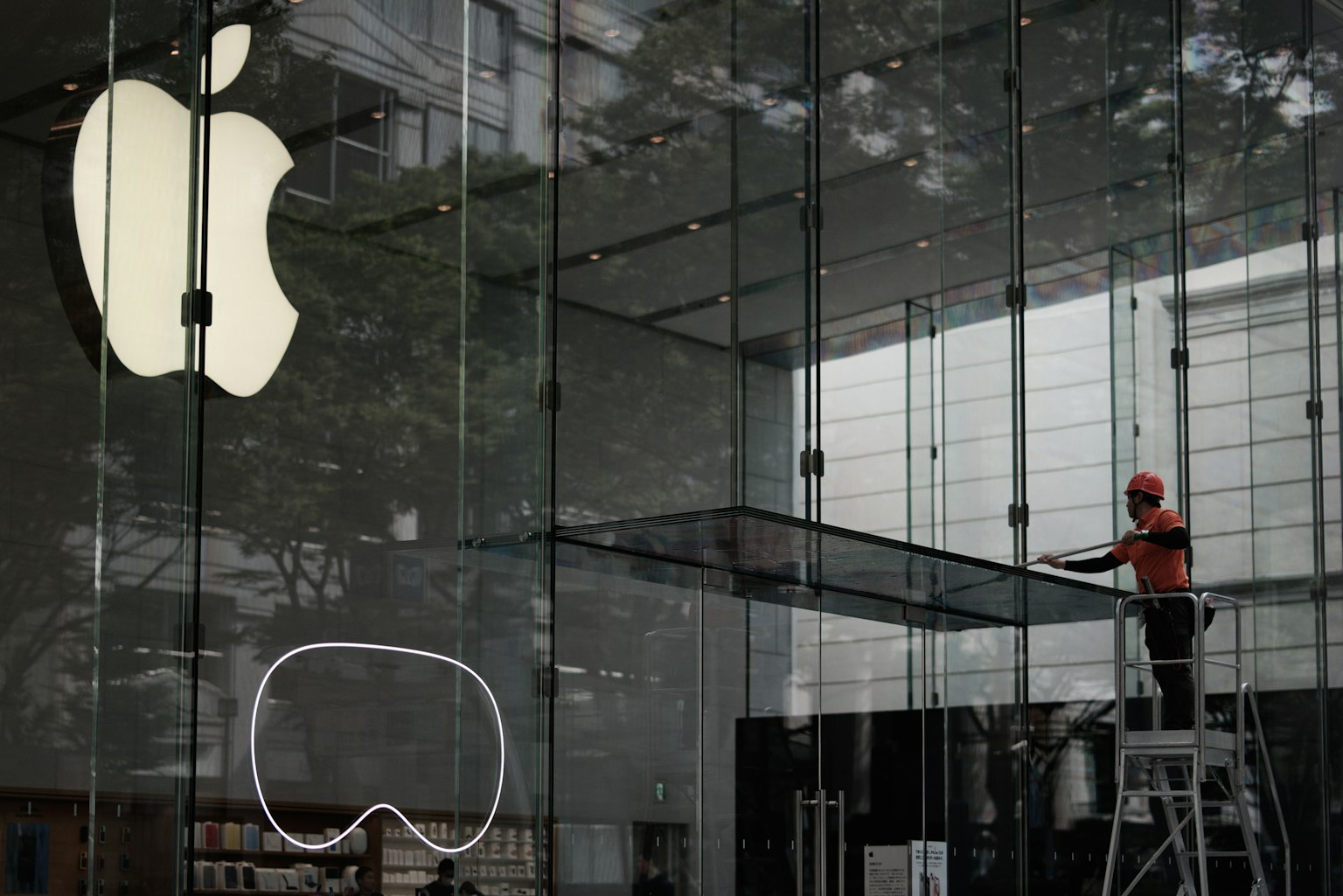 Worker adjusting display in front of Apple Store glass facade