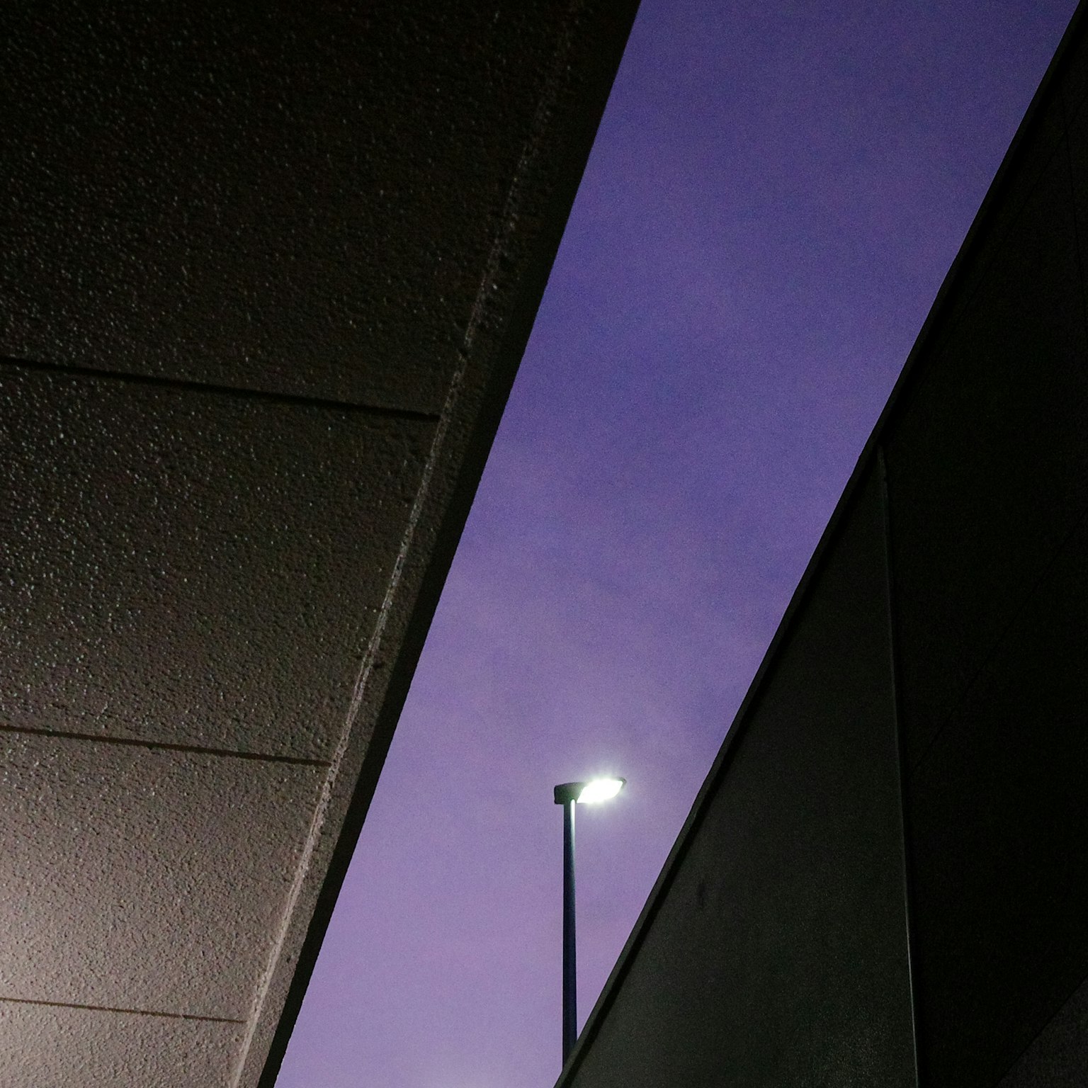 Vista de un cielo púrpura con una farola visible entre edificios