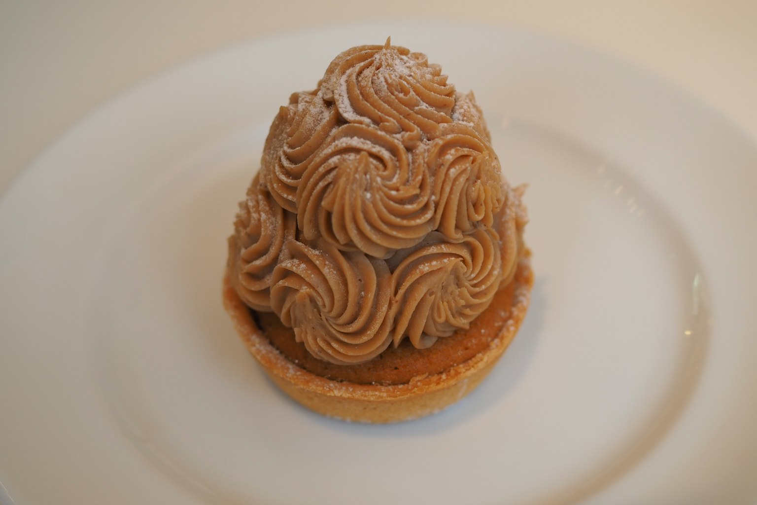 เค้กมงบลังค์อร่อยที่มีดีไซน์ครีมเกาลัดซับซ้อนบนจานสีขาว