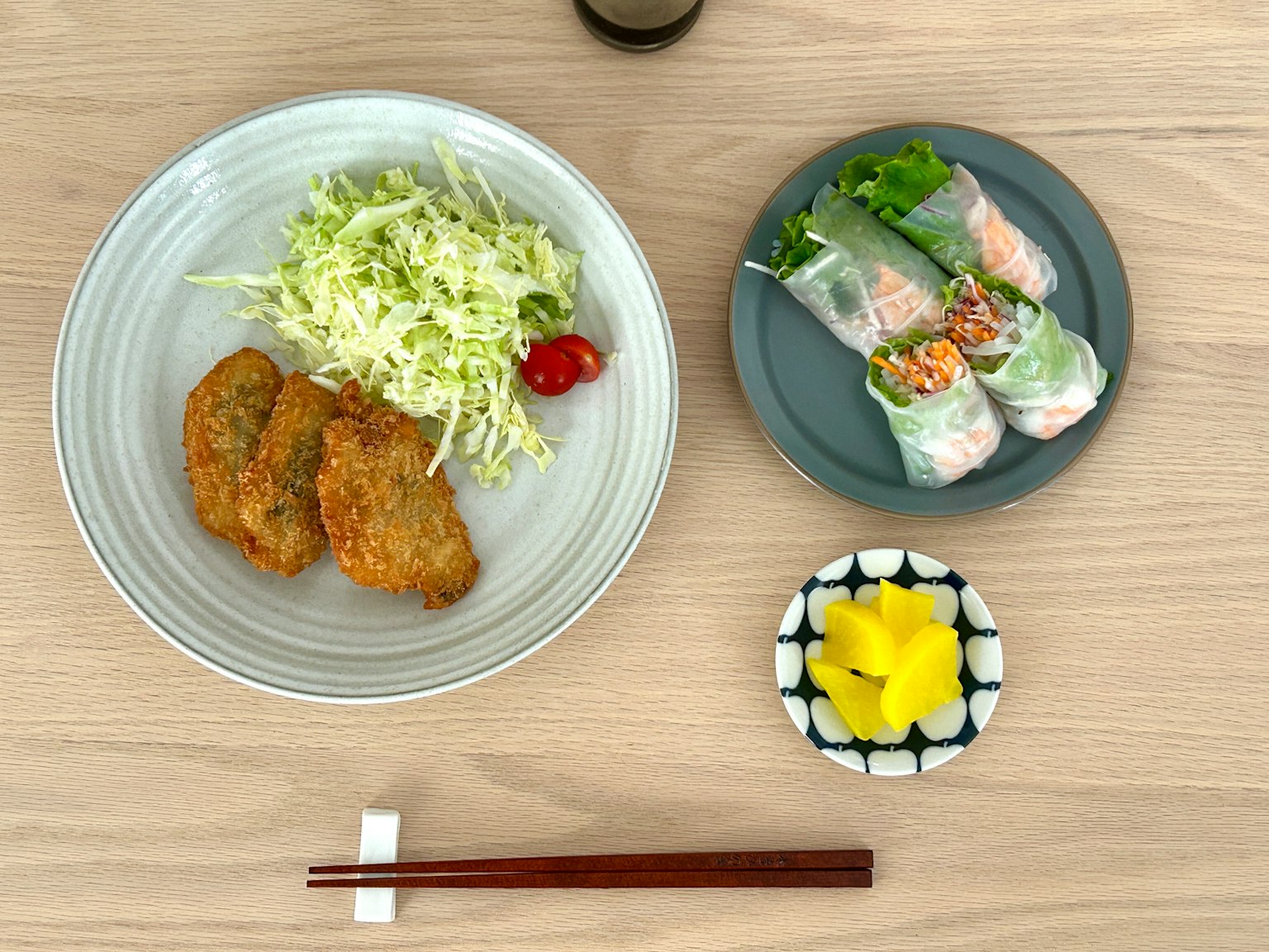 Un pasto con pollo fritto, cavolo tritato, involtini primavera e sottaceti gialli su un tavolo di legno