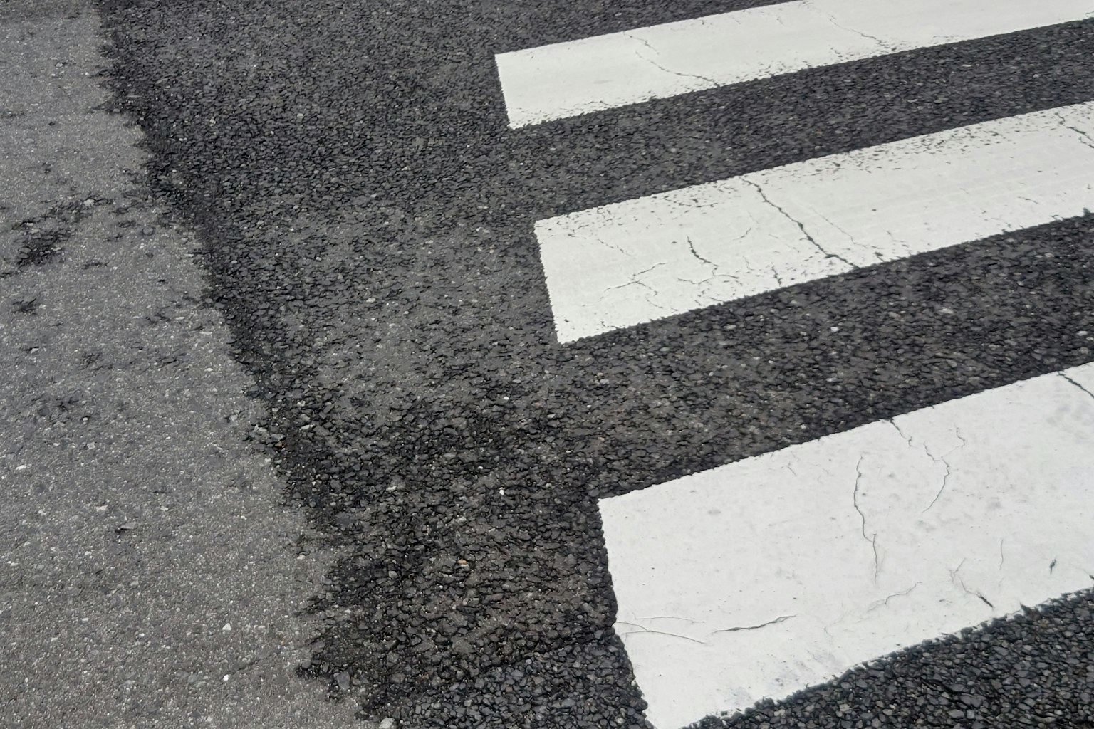 Close-up dari zebra cross dengan garis putih dan tekstur aspal