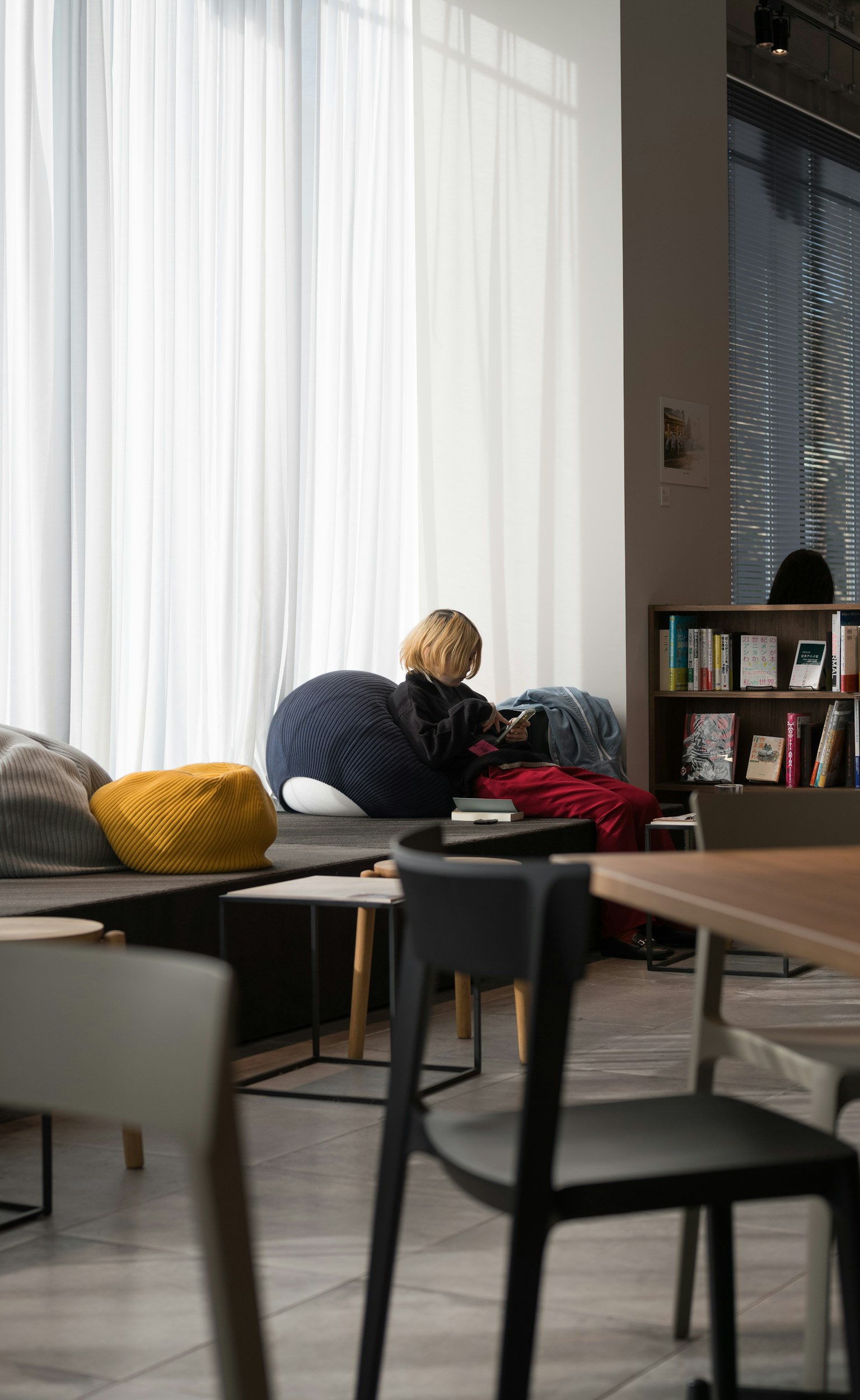 Eine Frau sitzt auf einem Sofa in einem hellen Café und benutzt ein Smartphone