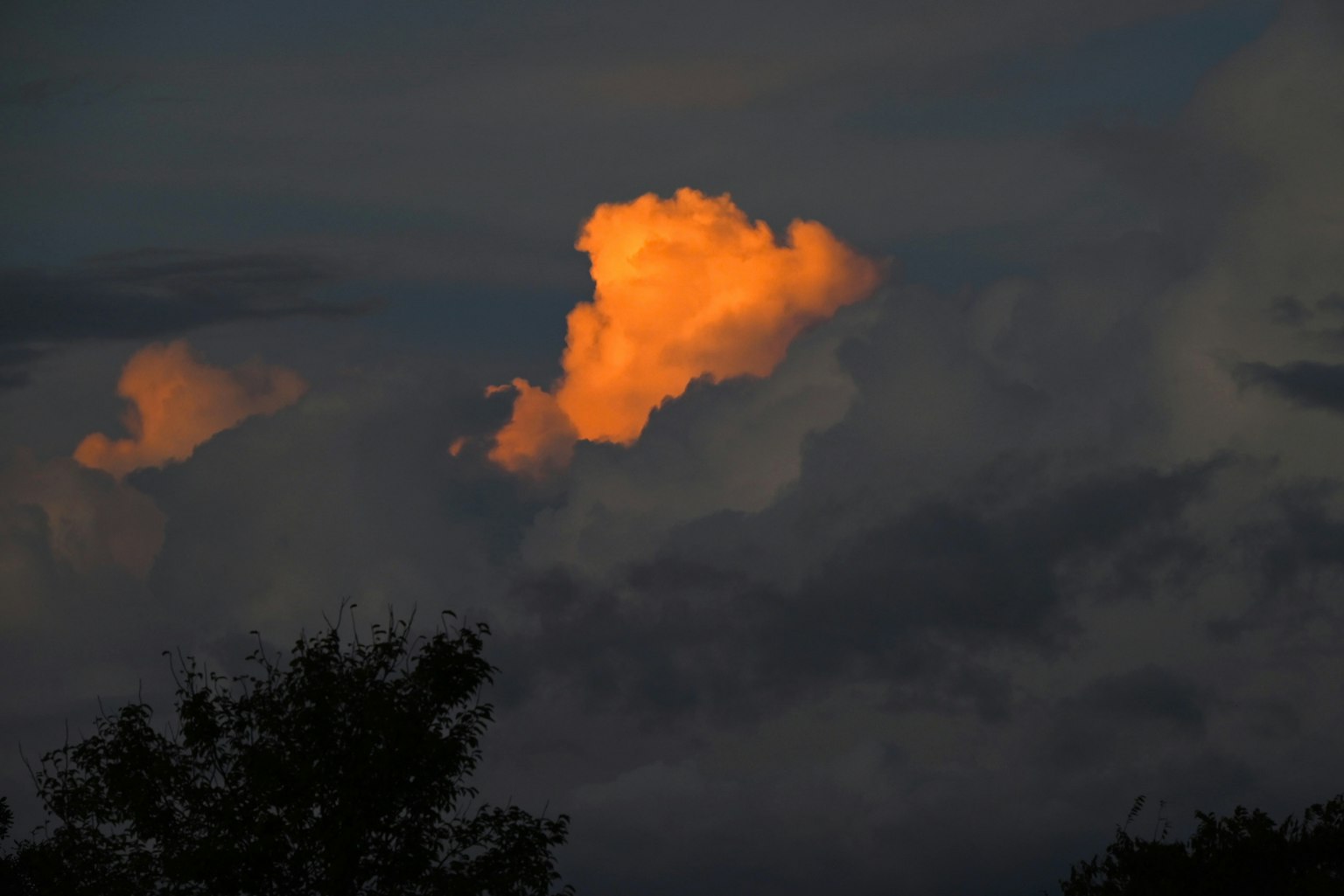Contraste d'un nuage illuminé par le coucher de soleil contre un ciel sombre