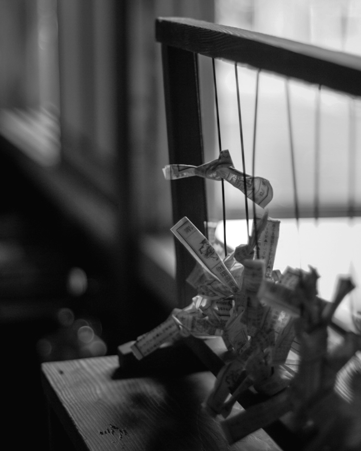 A black and white marionette hanging from a wooden stand
