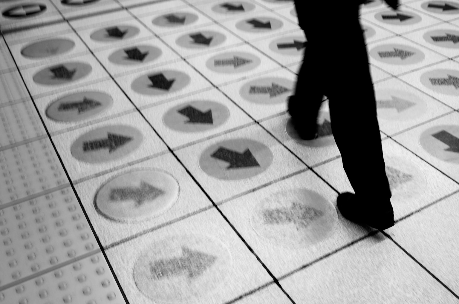 Una persona caminando sobre un suelo blanco y negro con flechas