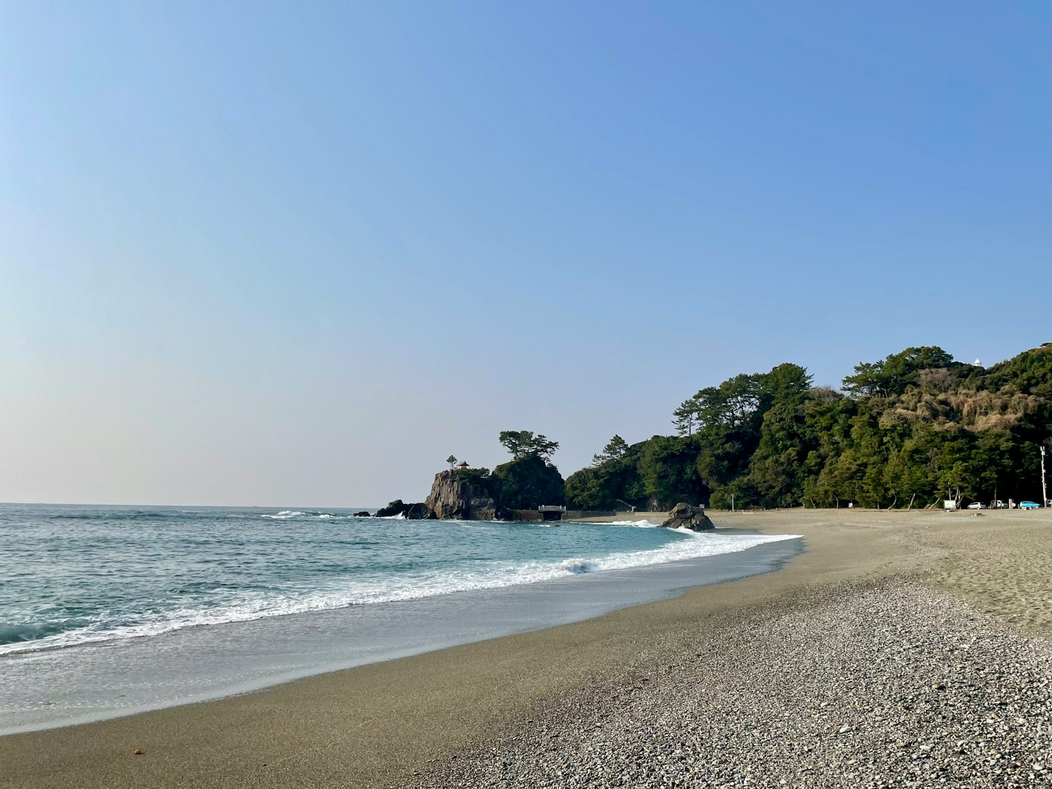 寧靜的海灘景觀，有柔和的海浪和清澈的藍天