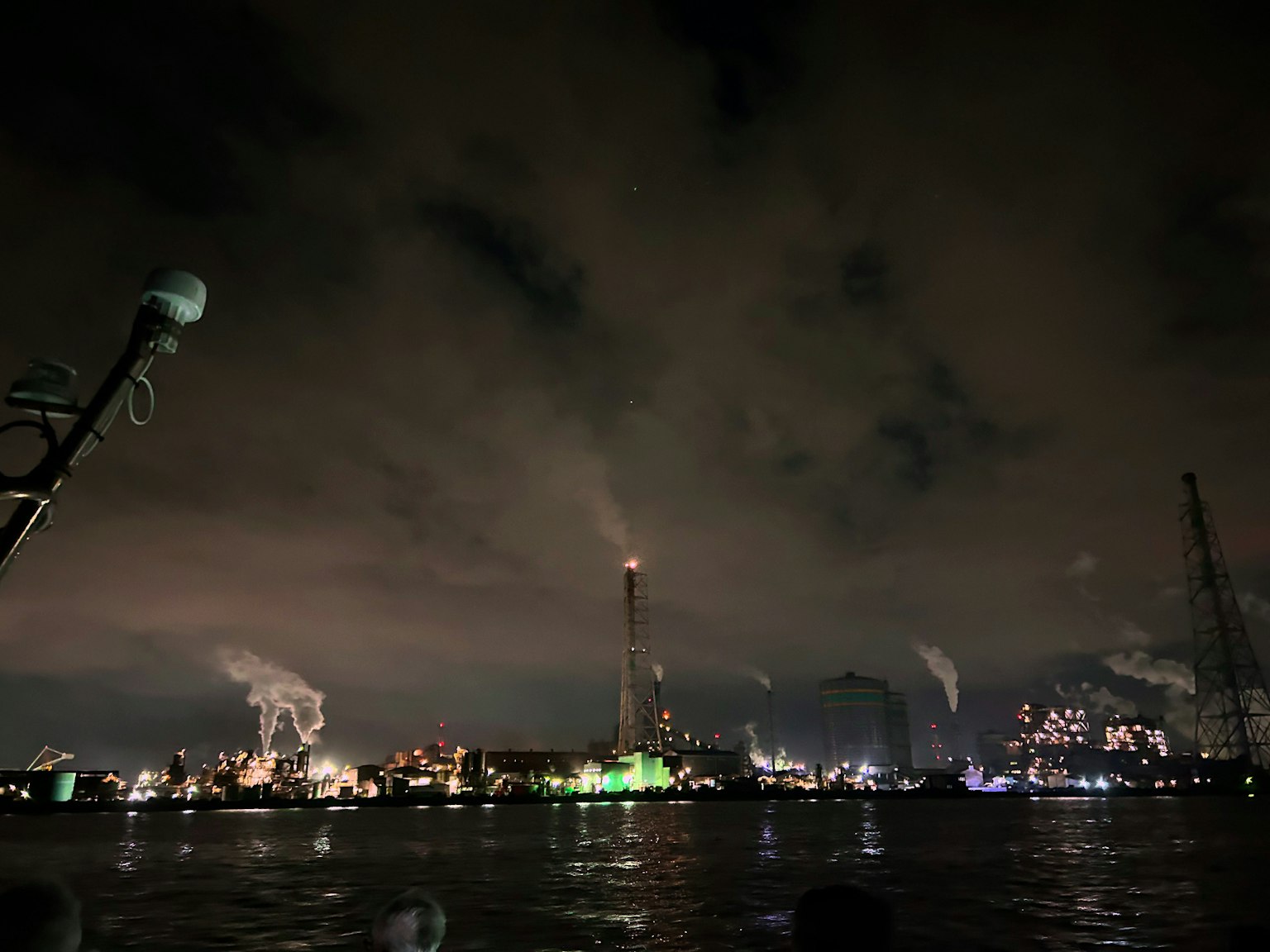Pemandangan malam area industri dengan cerobong asap dan lampu pabrik