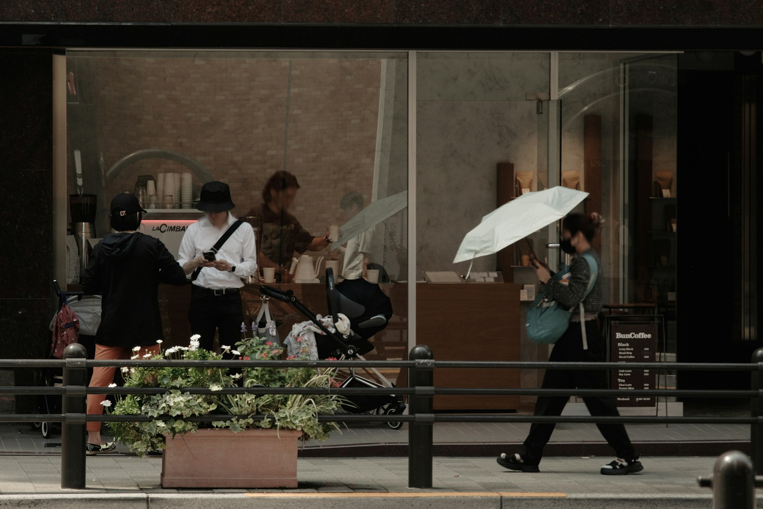 Scène de personnes devant un magasin avec une femme tenant un parapluie