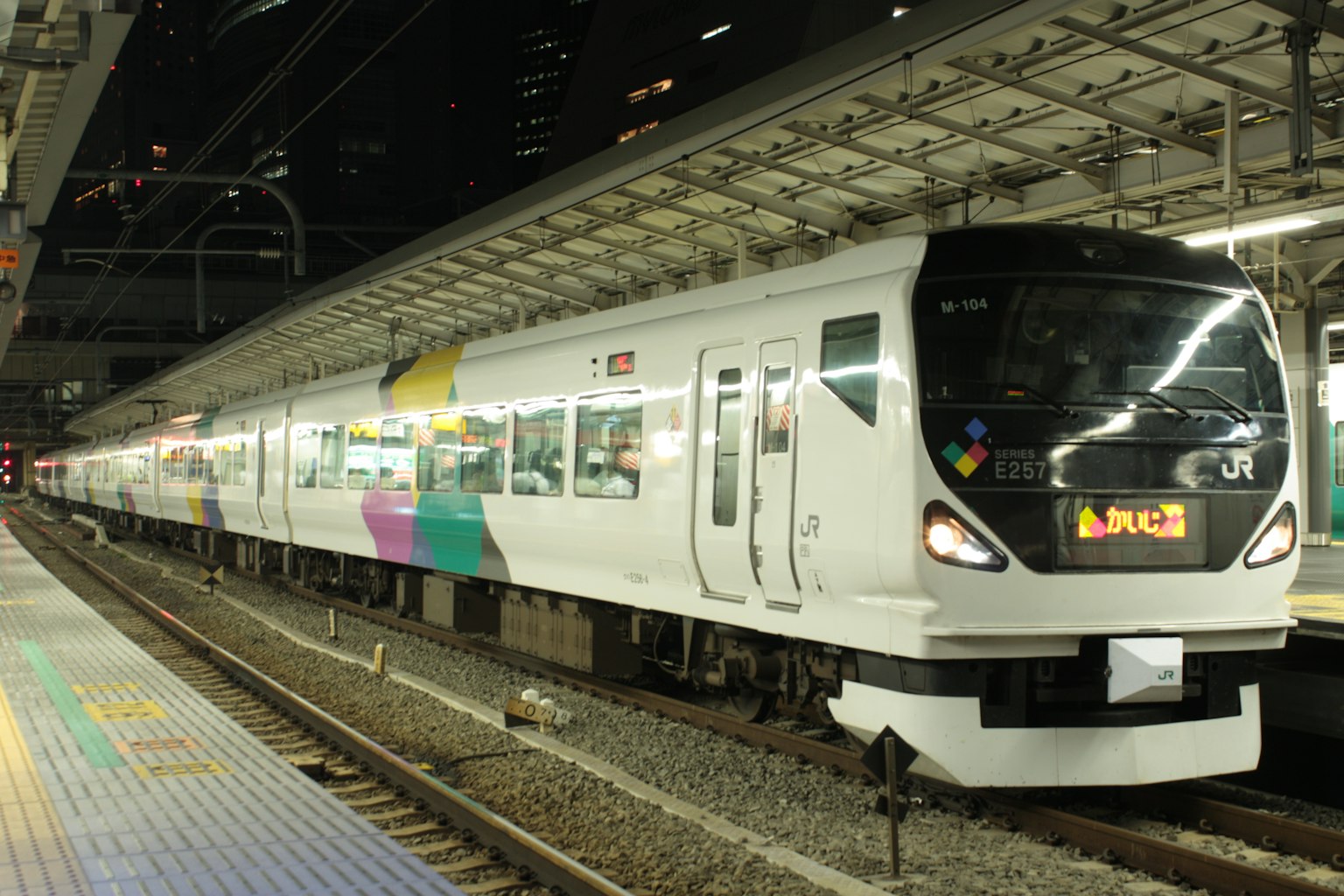 一列白色和多彩的火車在夜間停靠在車站