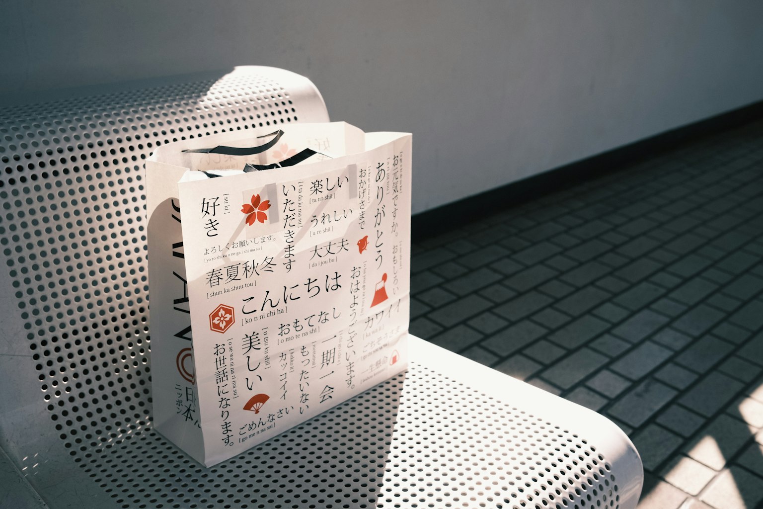 一個白色的袋子上面有日文文本，放在長椅上