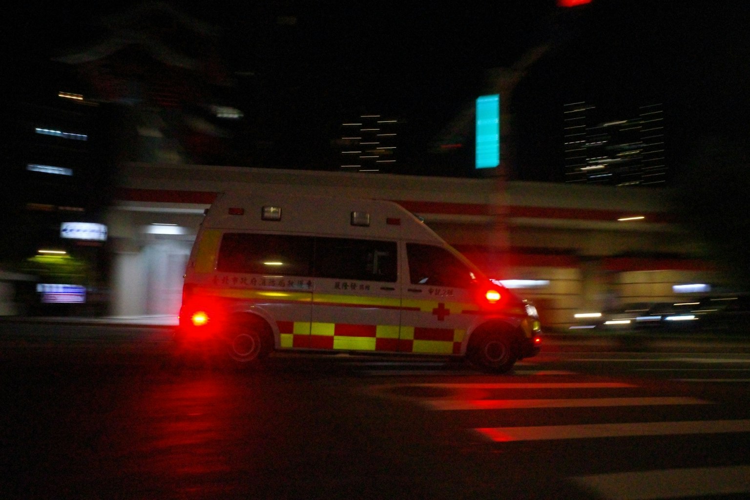 夜の街を走る救急車 赤いライトが点灯している