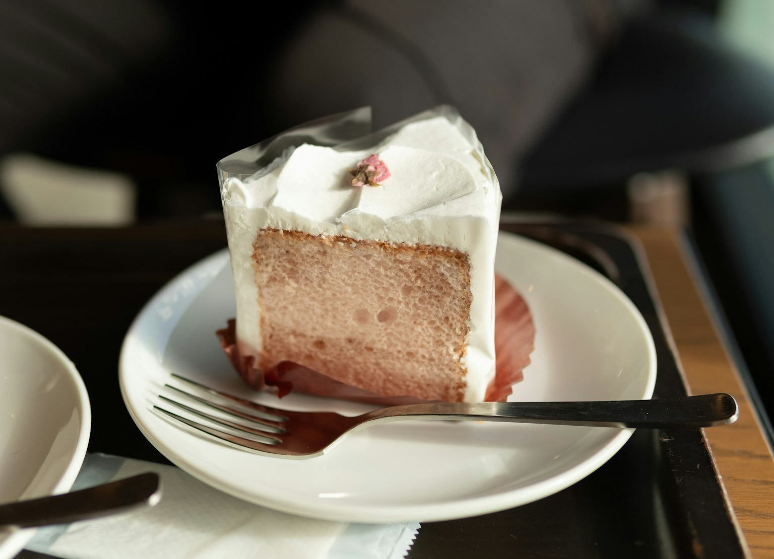 Una fetta di torta con crema e una ciliegia su un piatto bianco
