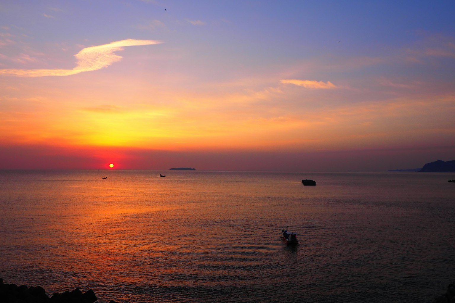 Beautiful landscape of sunset over the sea with a boat gliding on the water