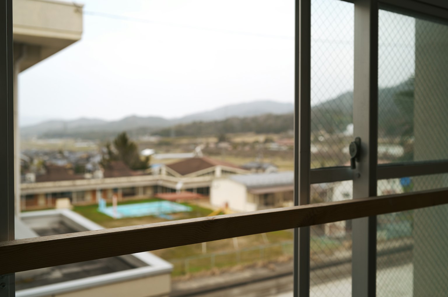 View from a window showing mountains and a residential area with a pool