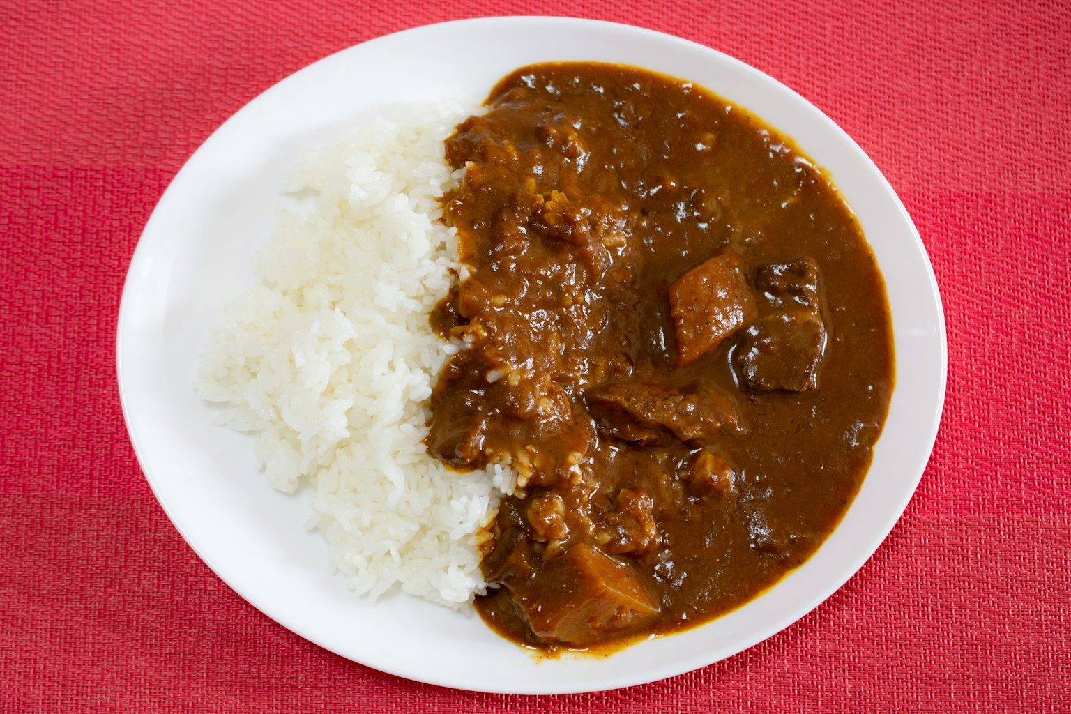 Un plato de arroz servido con una rica salsa de curry marrón y trozos de carne