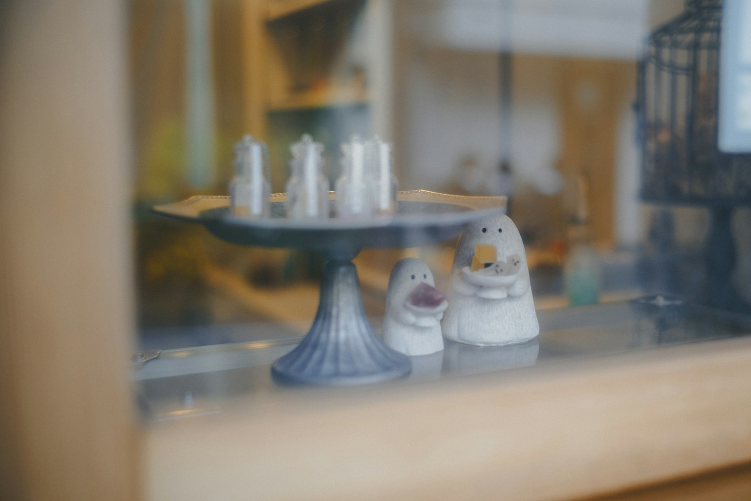 窓越しに見える小さな陶器の動物たちとキャンドルスタンド