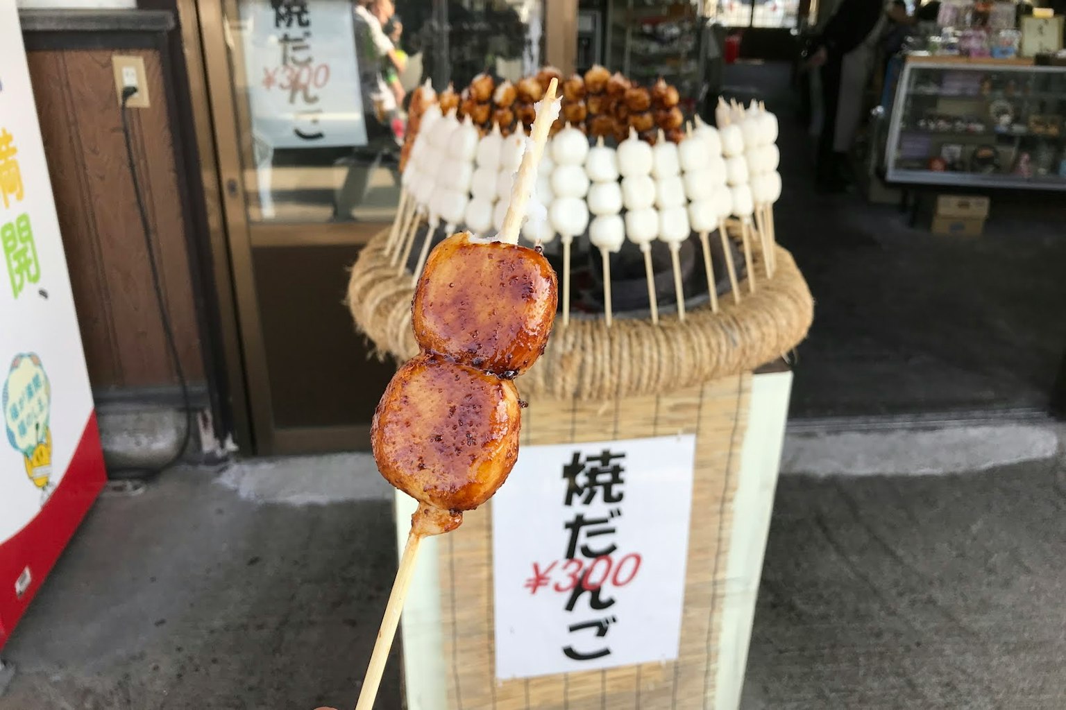 Gegrillte Dango-Spieße an einem Straßenstand mit einem Schild