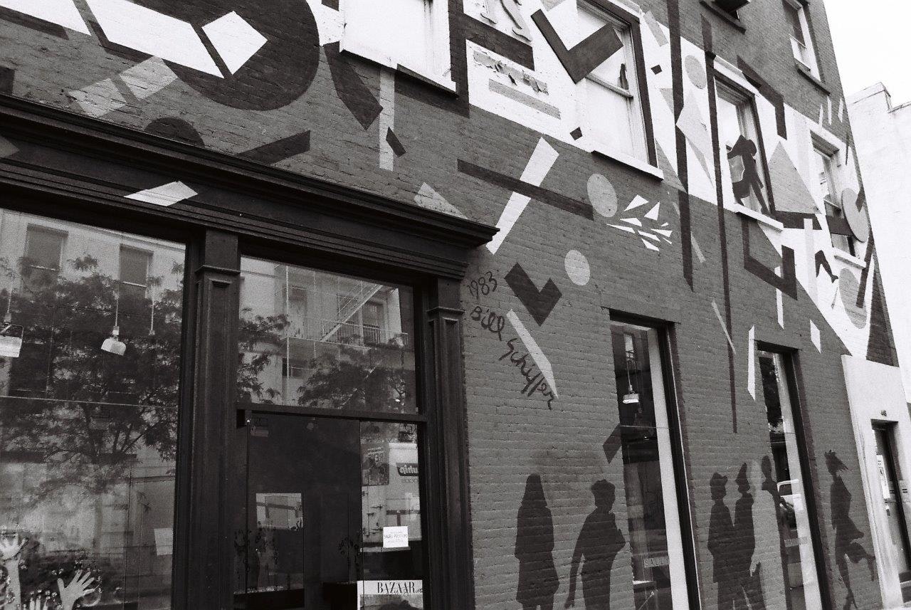 alley building facade with abstract stencil art and windows